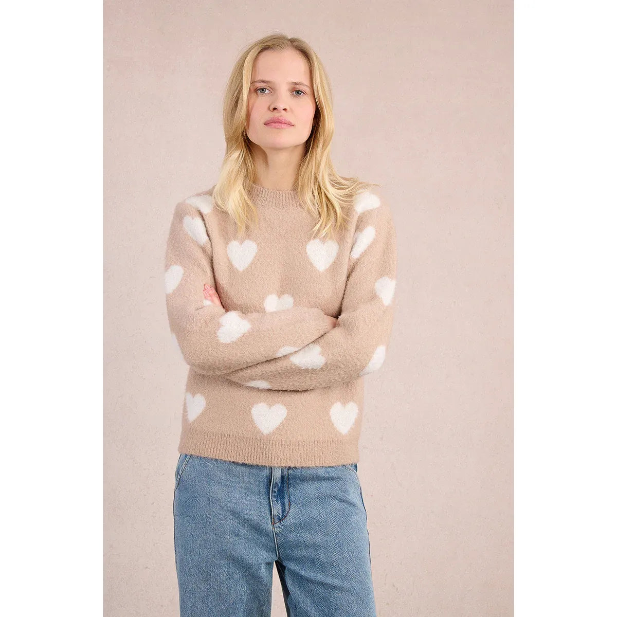 Model wearing a beige heather knit Molly Bracken Heart Sweater with white hearts, long sleeves, and round neckline.