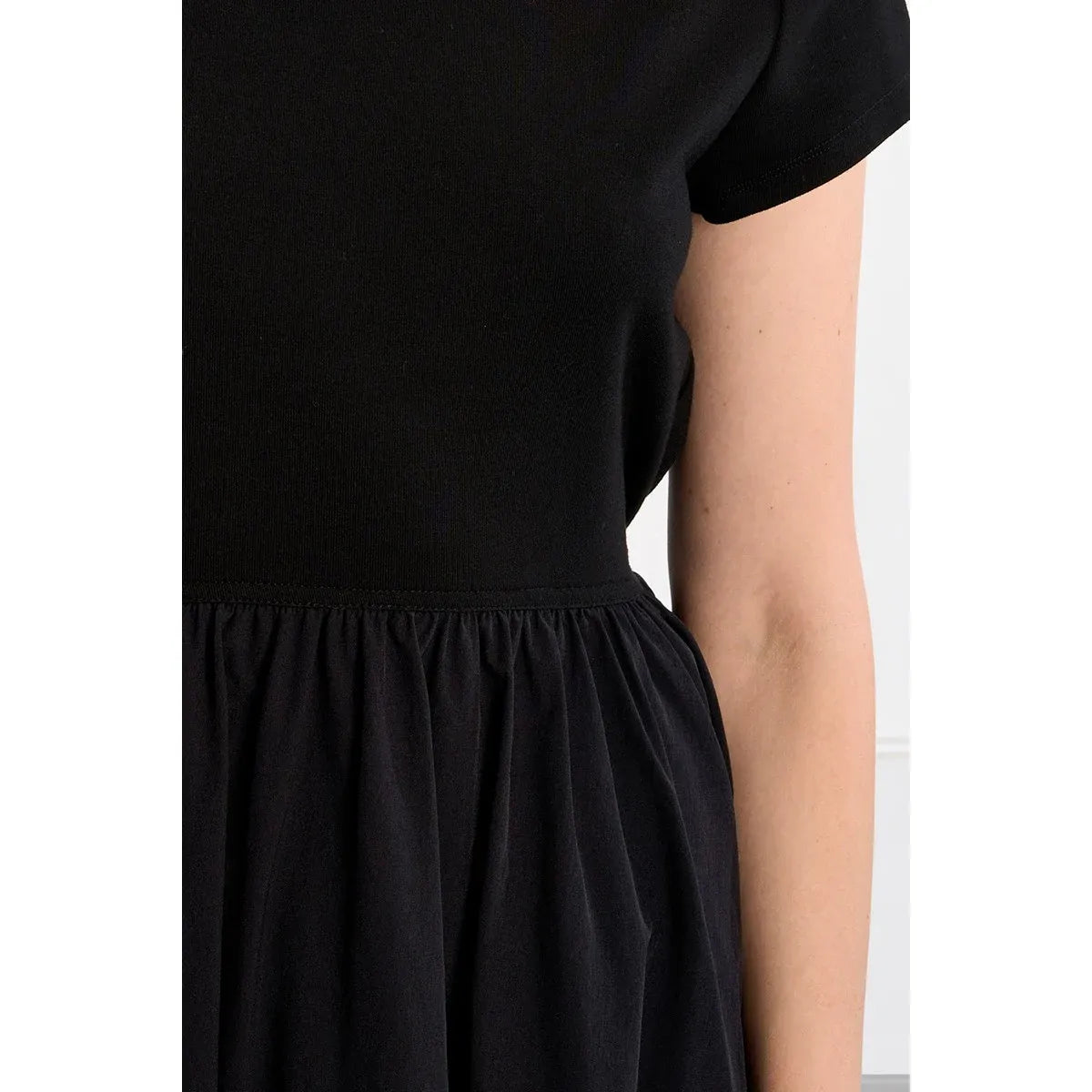 Black nylon drawstring mini dress with a boat neck, short sleeves, and a gathered waist.
