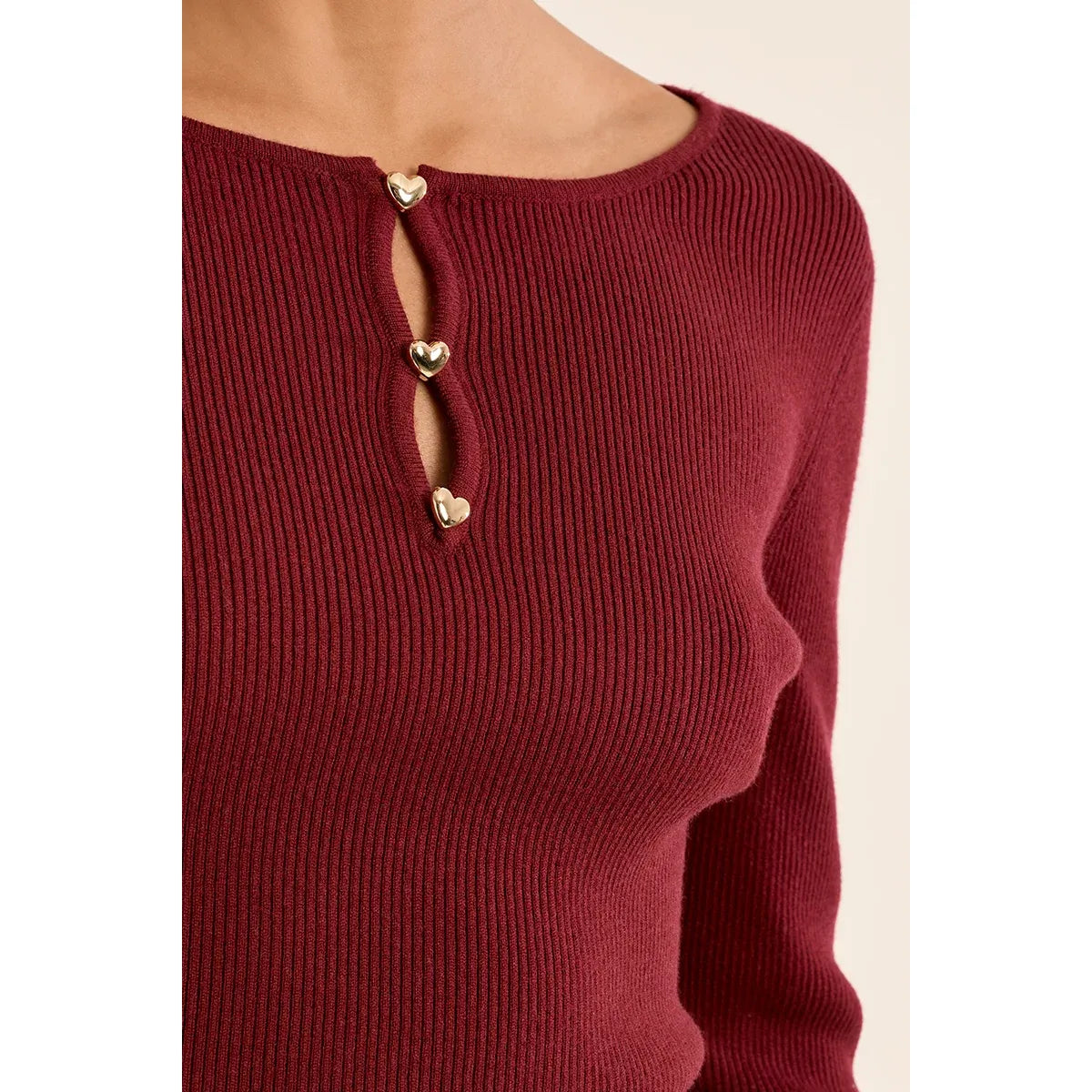 Burgundy fine ribbed sweater with gold heart buttons at the round neck slit.