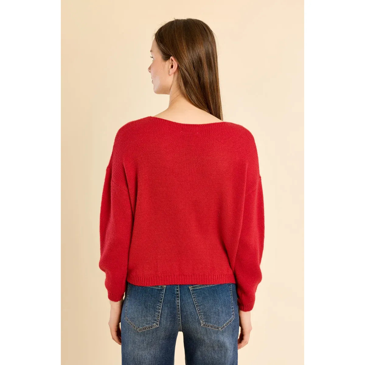 Back view of a red round neck knit sweater with relaxed fit and ribbed hem, styled with blue jeans.
