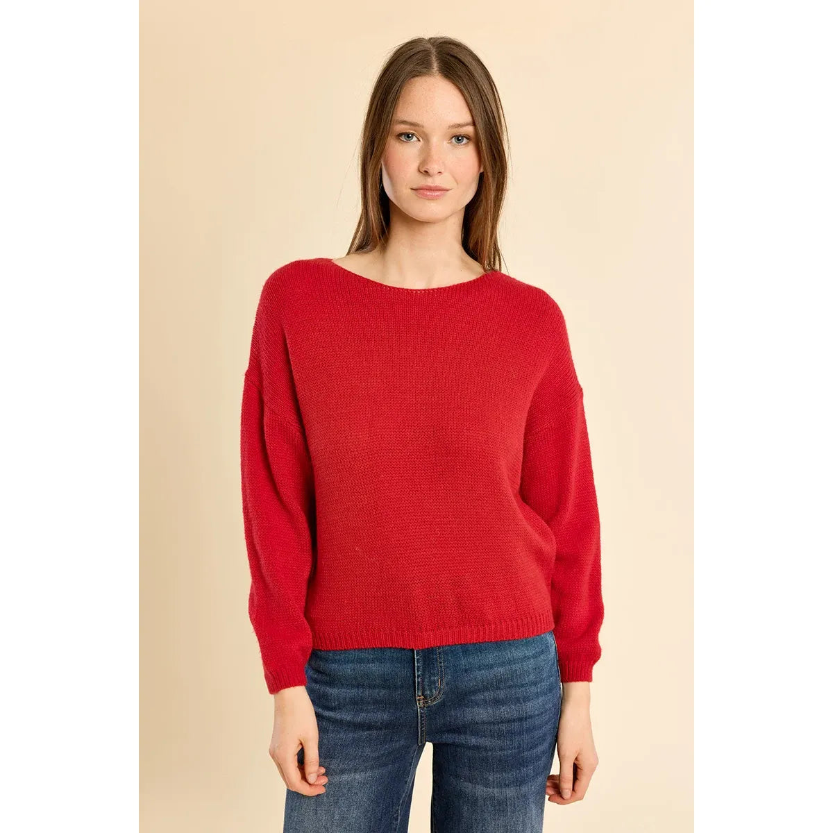 Red knit round neck sweater with low armholes and ribbed trim at collar, cuffs, and waist, styled with blue jeans.