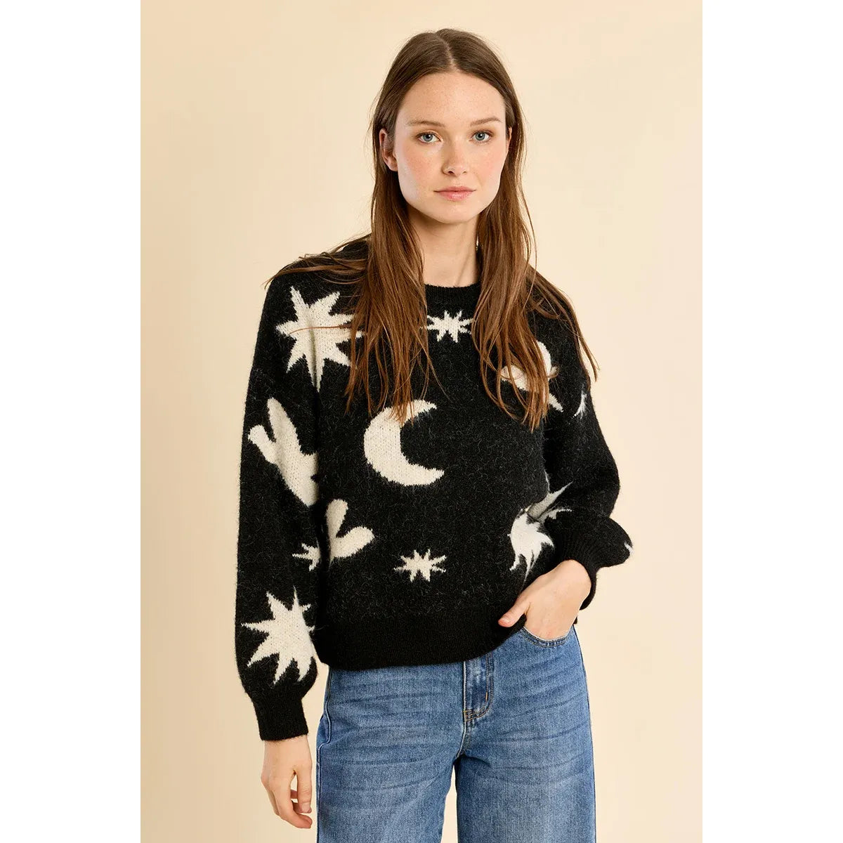Black knit sweater with white stars, moons, and bird motifs features balloon sleeves and ribbed trim, styled with blue jeans.