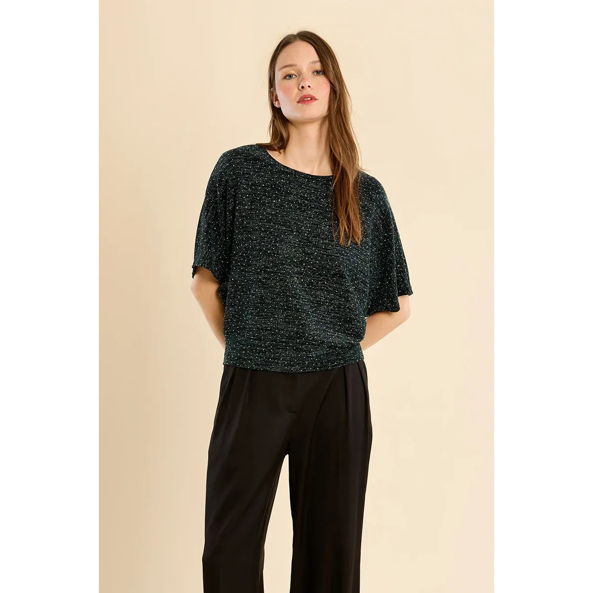Sparkly dark rhinestone top with wide short sleeves and metallic shimmer, styled with black tailored pants for a festive look.