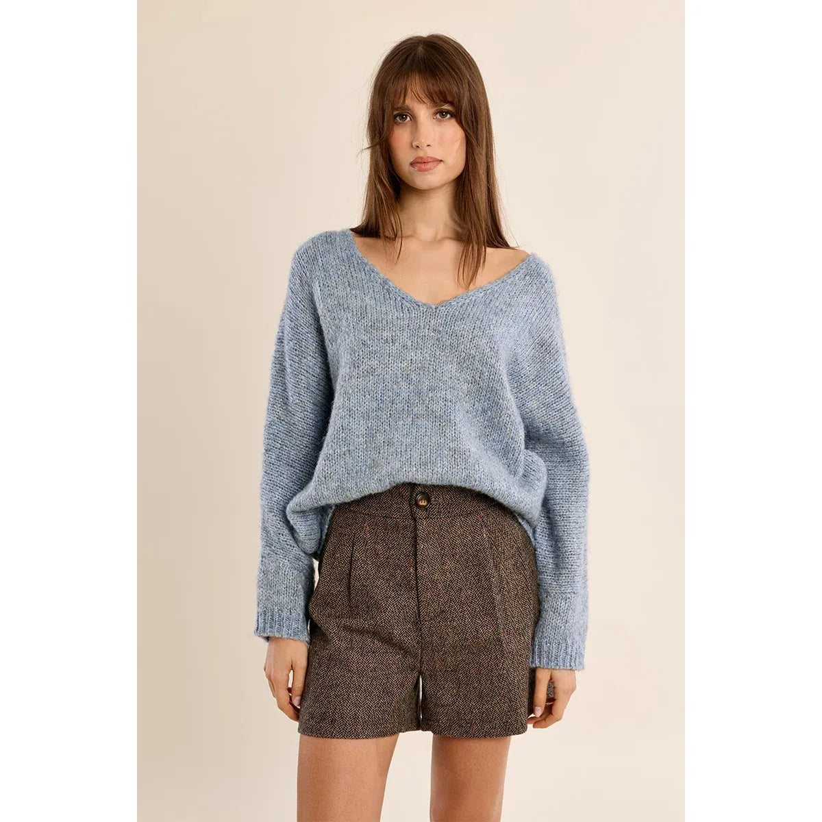 Light blue V-neck knit sweater with long sleeves and a relaxed fit, styled over herringbone shorts for a casual look.