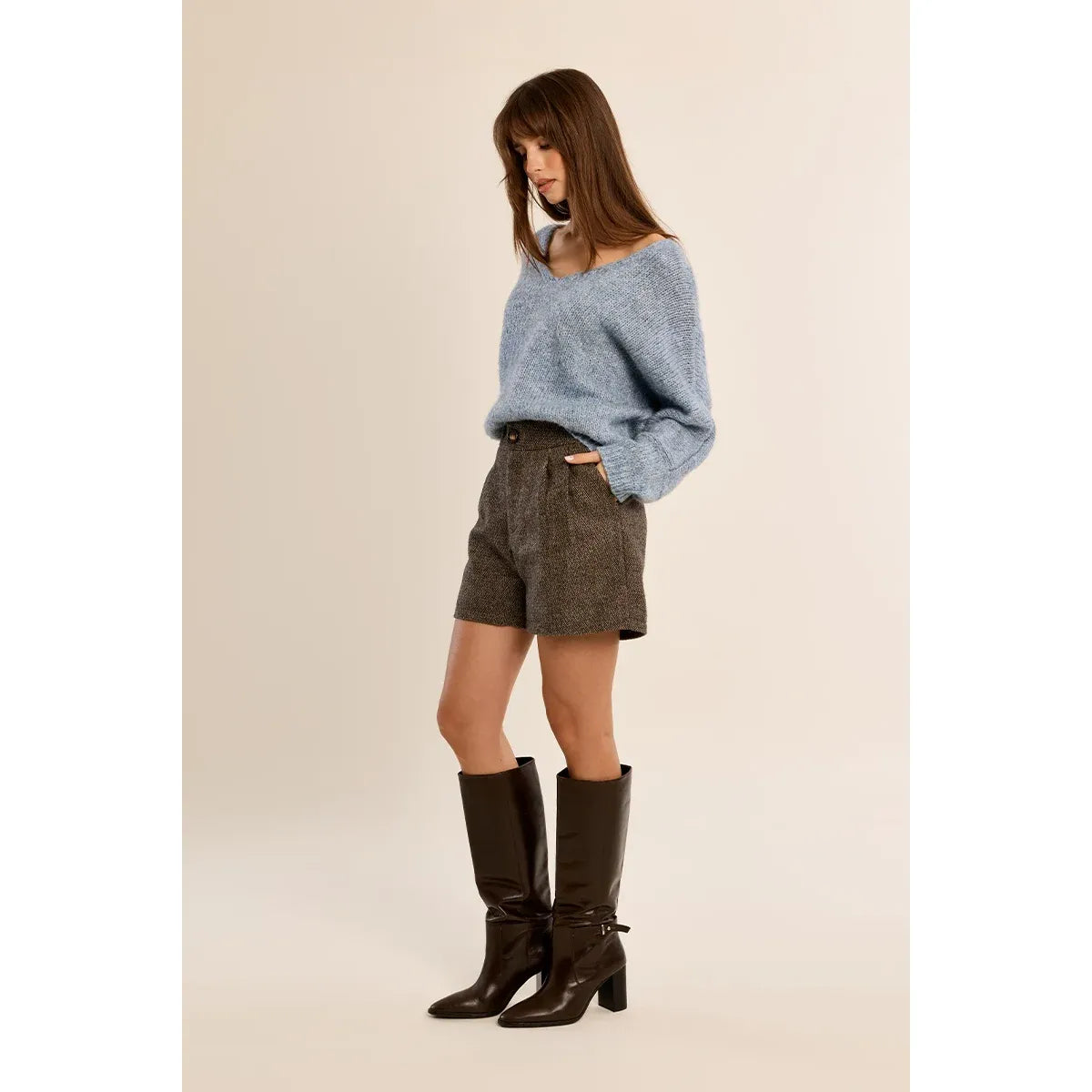 Light blue V-neck knit sweater with long sleeves, styled with brown shorts and tall boots for a casual fall look.