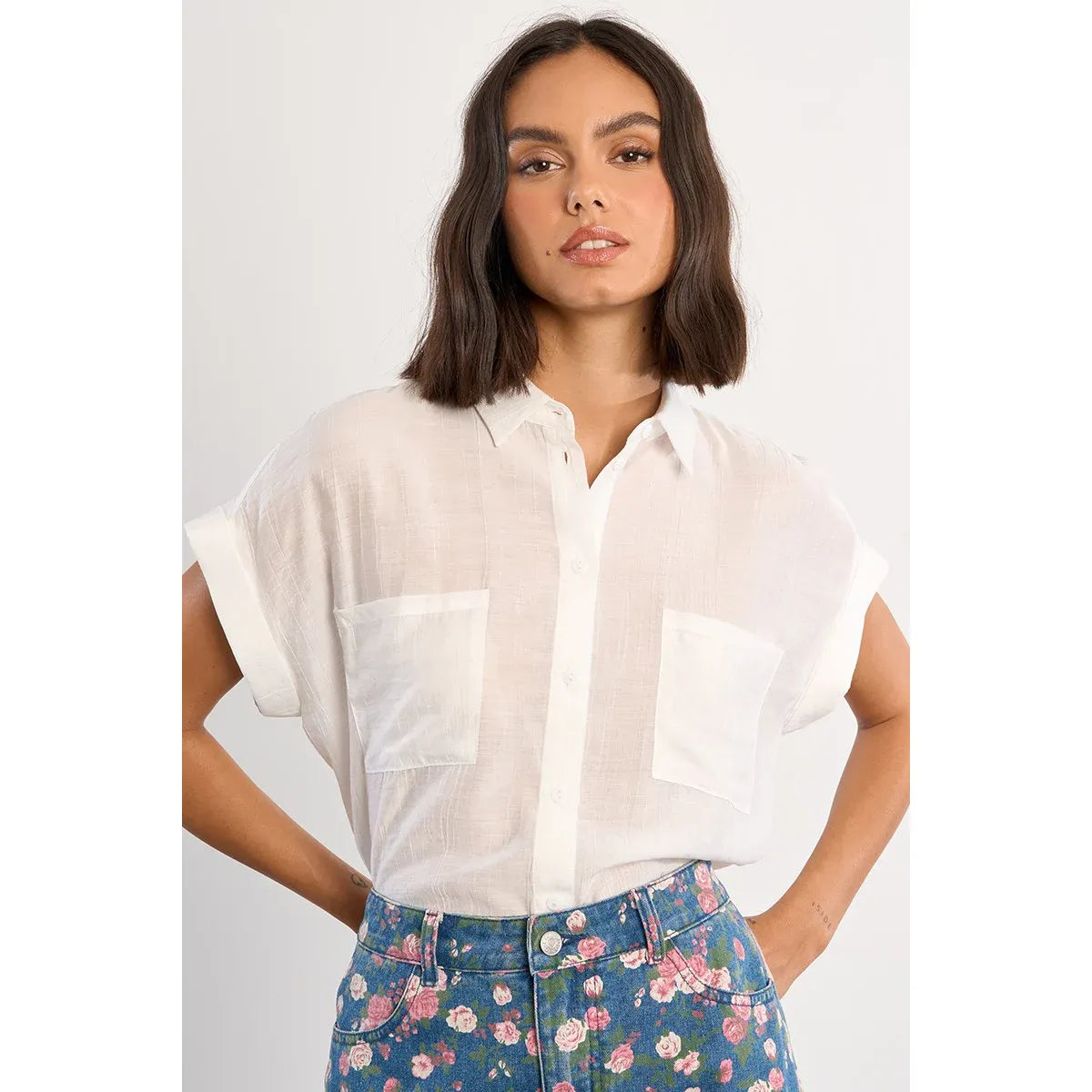 Molly Bracken white woven short-sleeve blouse with front buttons and two chest pockets, paired with a floral skirt.