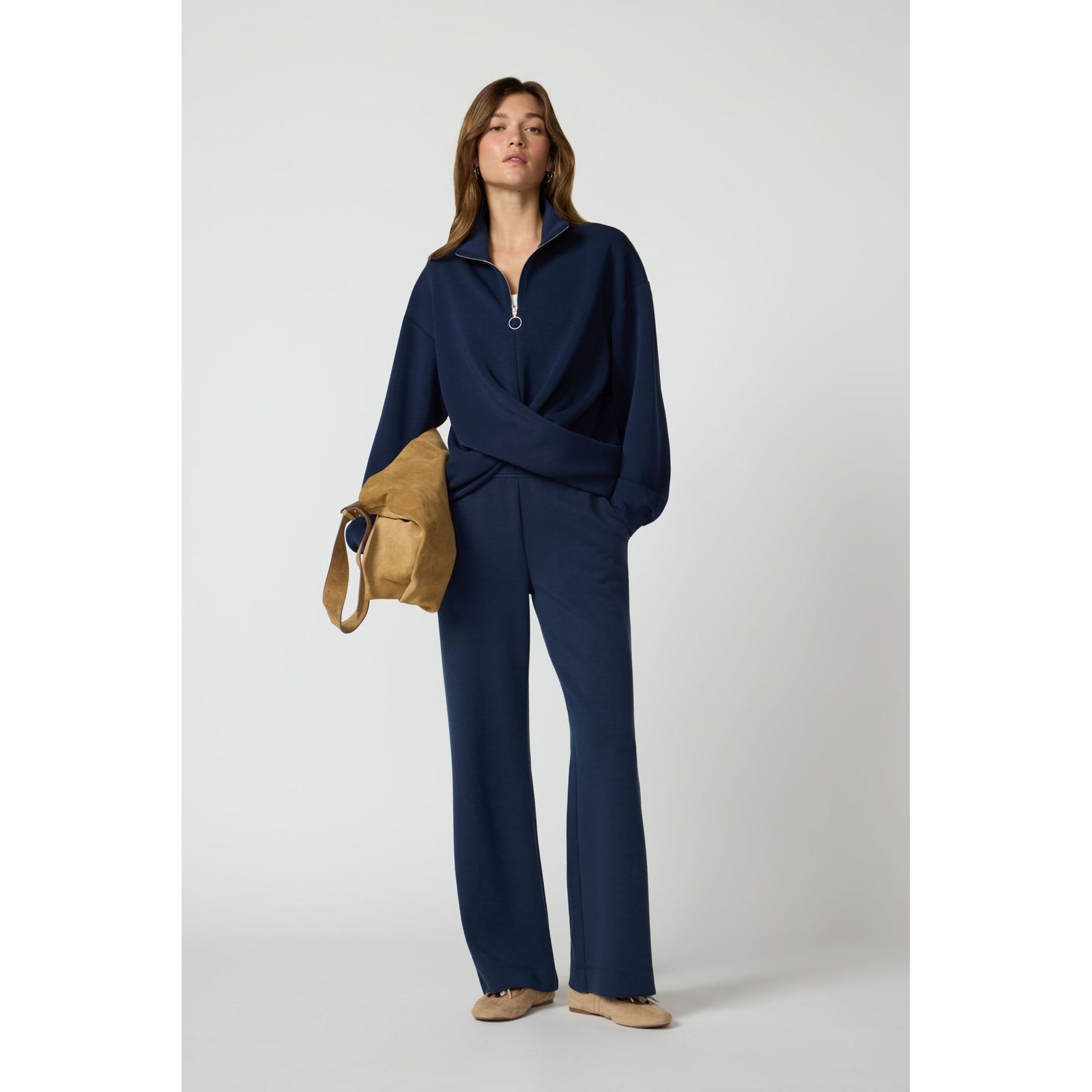 Navy blue crossover pullover with quarter-zip and dropped shoulders paired with matching wide-leg trousers and tan accessories.