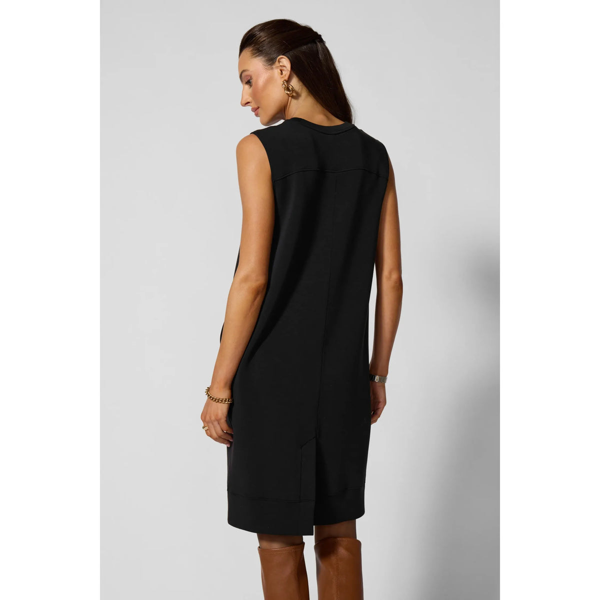 Back view of black sleeveless dress featuring curved back yoke, structured fit, practical insert pockets, and ribbed hem.