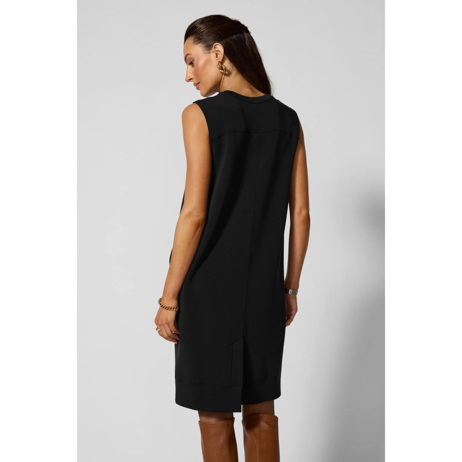 Back view of black sleeveless dress featuring curved back yoke, structured fit, practical insert pockets, and ribbed hem.