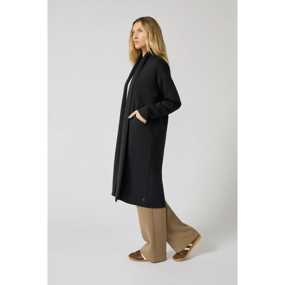 Black long cardigan with clean longline silhouette draping effortlessly over wide-leg trousers for polished loungewear comfort.