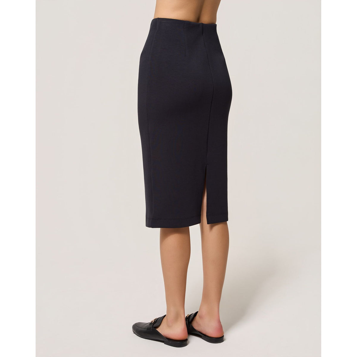 Dark navy Dreamweave pencil skirt with a back slit, elasticized waist, and a sleek fitted midi silhouette worn with black loafers.