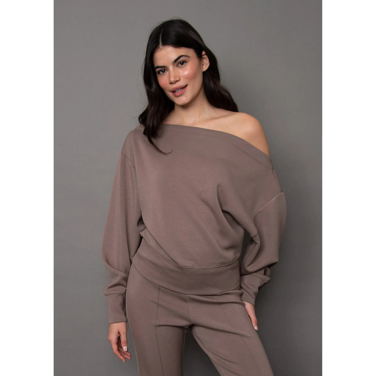 Model wearing brown Ophelie soft knit drop shoulder top with off-shoulder detail and matching pants for a relaxed, sophisticated look.
