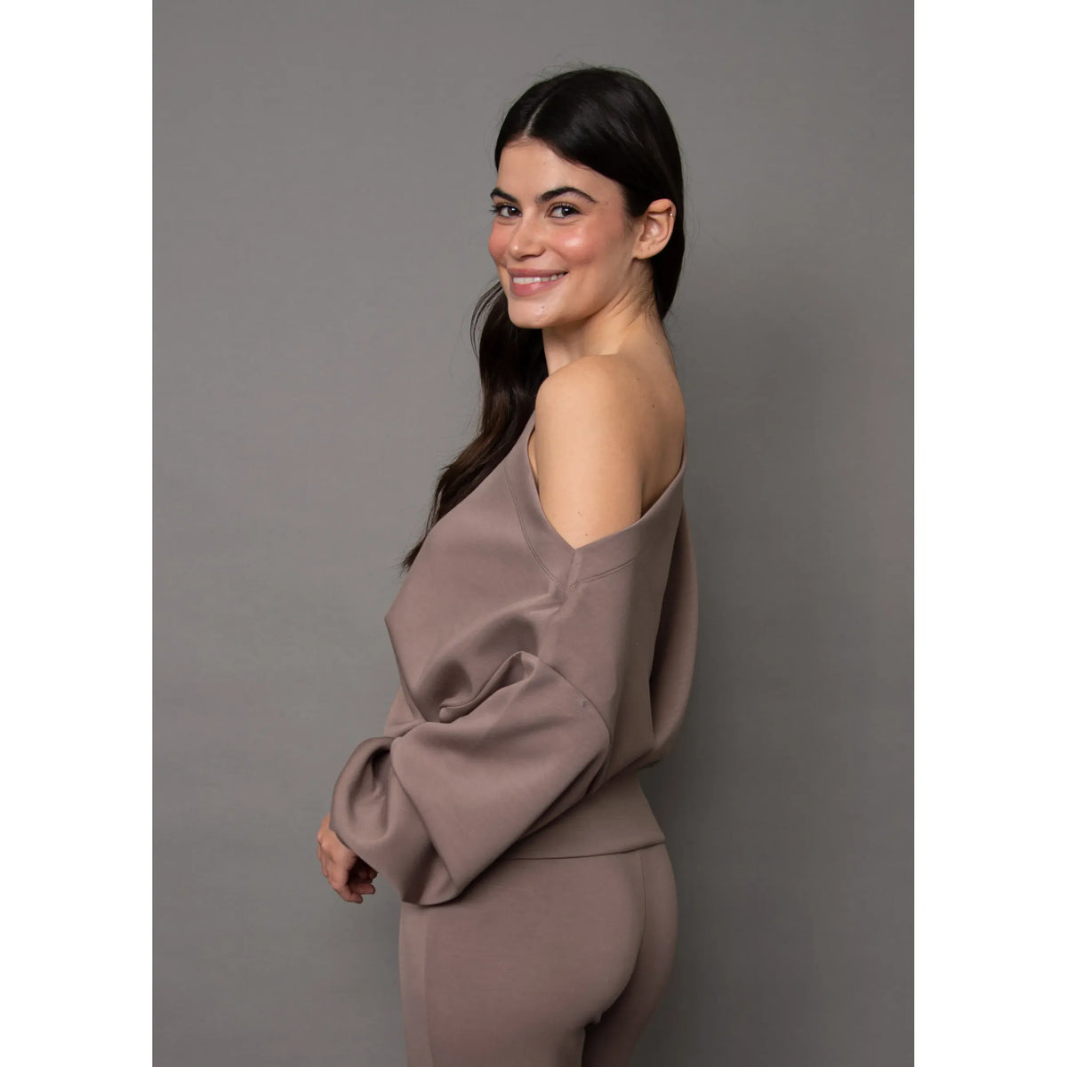 Woman wearing a mauve soft knit drop shoulder top with long sleeves, showcasing relaxed ease and effortless sophistication.