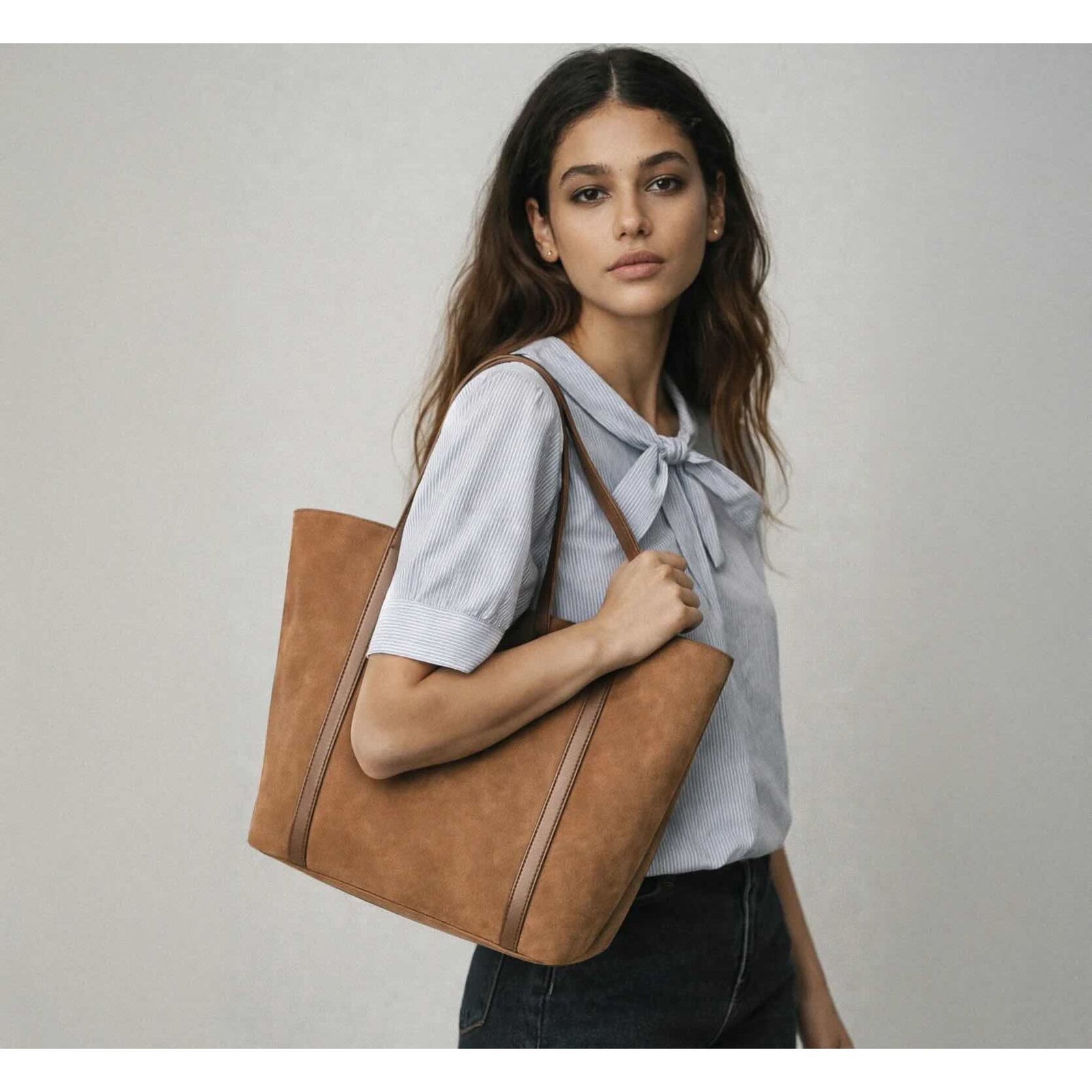 Model carrying a pale brown suede-effect handbag with clean lines and a shoulder strap.