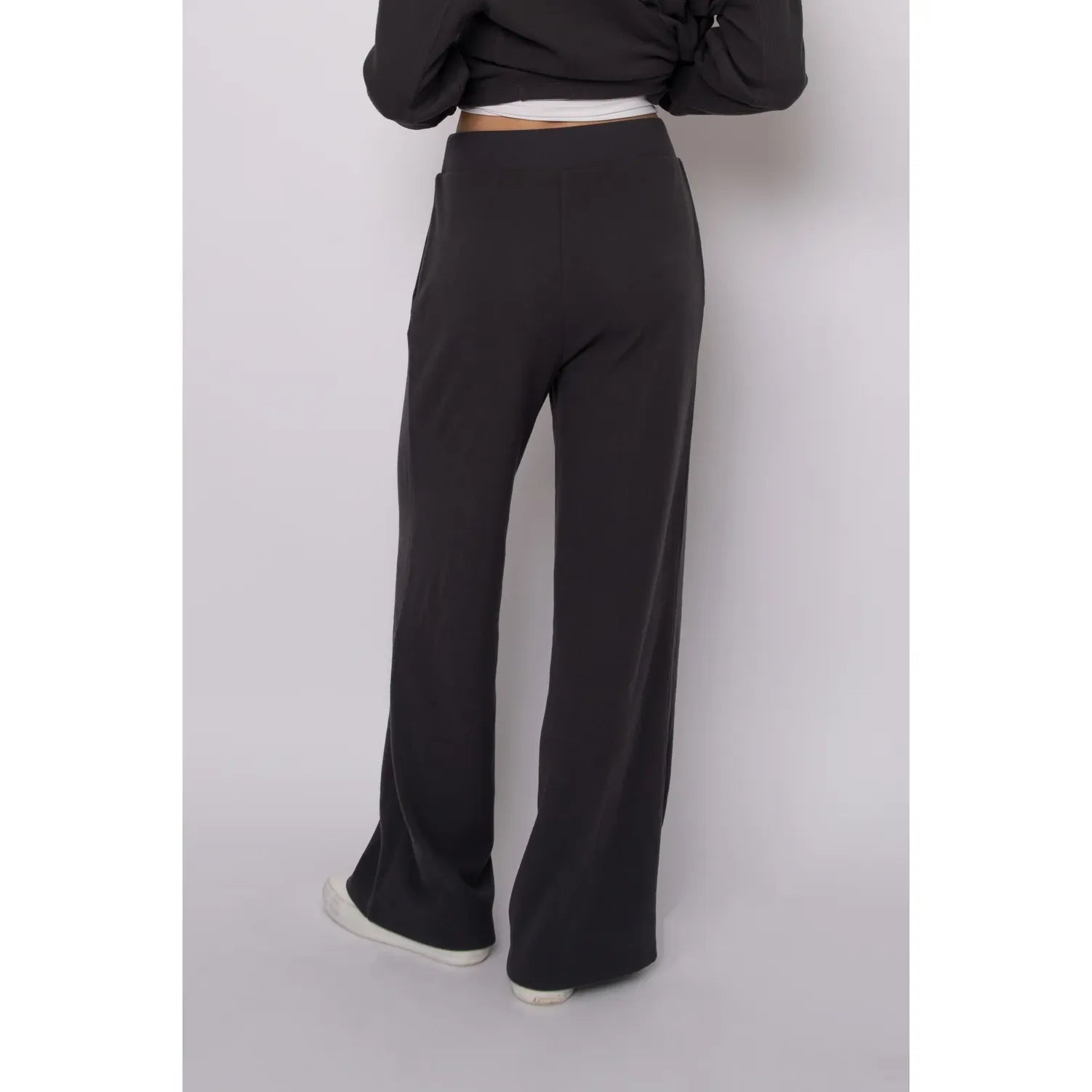 Back view of dark grey wide leg waffle knit drawstring pants with a relaxed fit and elastic waistband for cozy loungewear style.