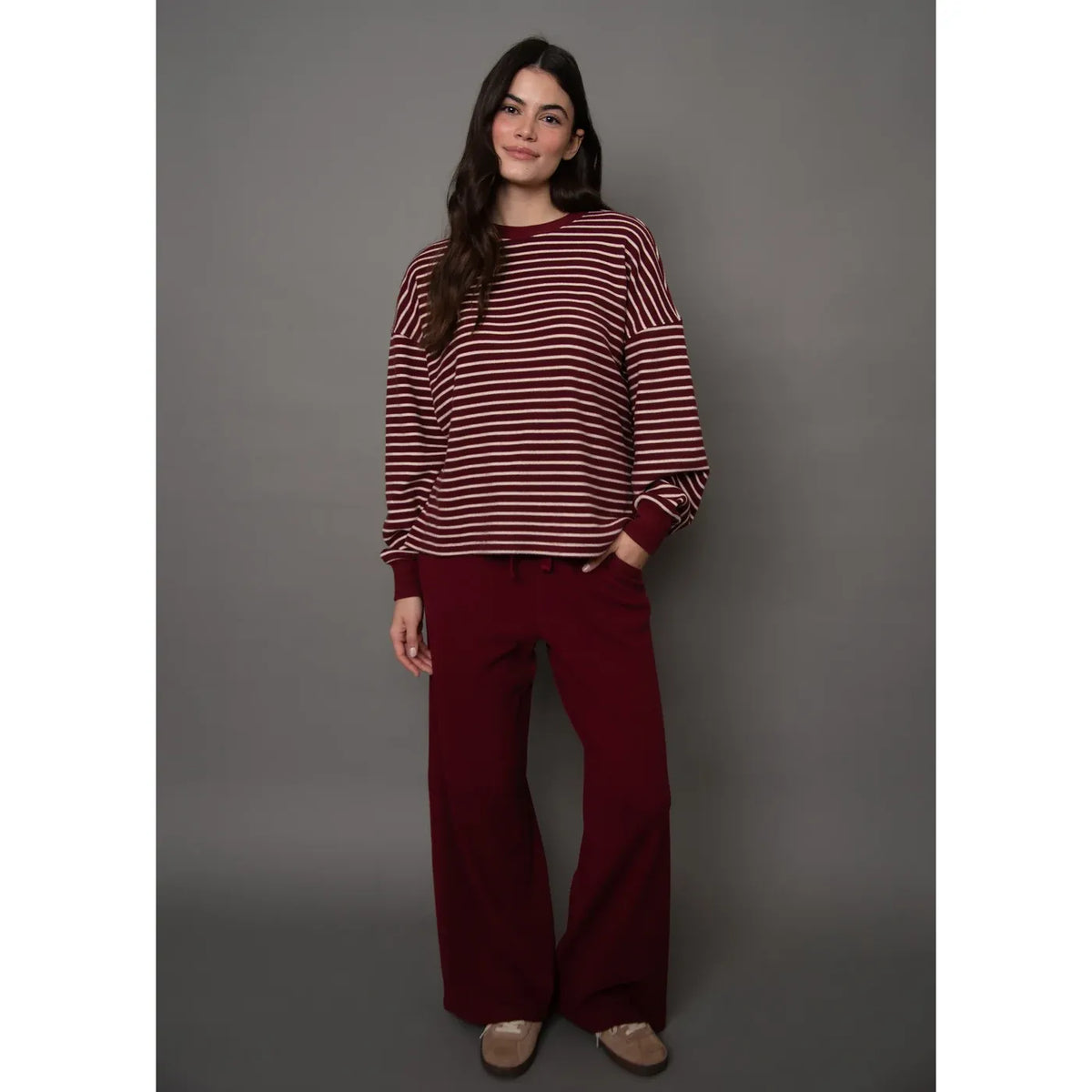 Burgundy waffle-knit drawstring wide leg pants with a relaxed silhouette, styled here with a matching striped top.