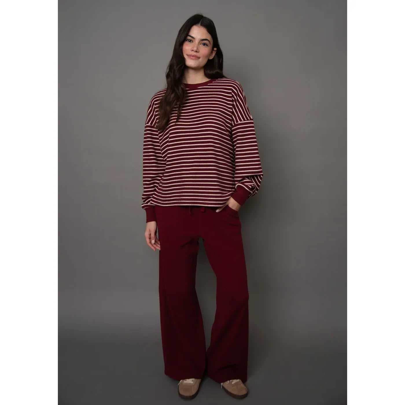 Burgundy waffle-knit drawstring wide leg pants with a relaxed silhouette, styled here with a matching striped top.