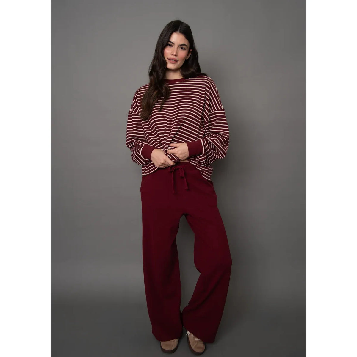 Model wearing burgundy waffle drawstring wide leg pants paired with a red and white striped sweater for cozy loungewear style.