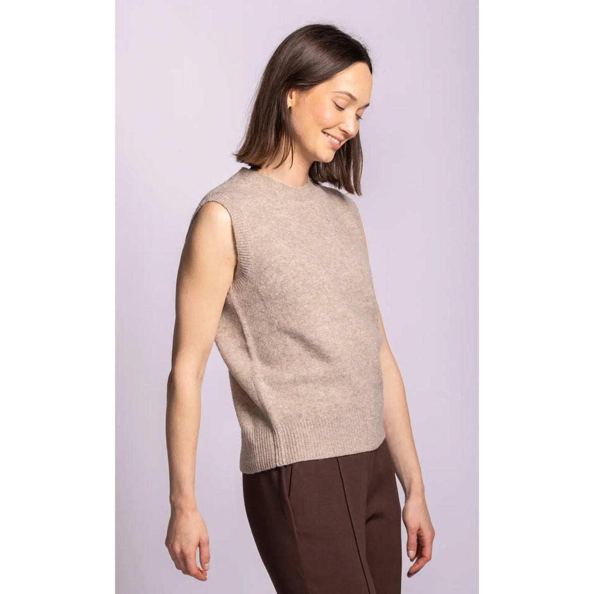 Beige sleeveless ribbed sweater with structured shoulders and hem, crafted from soft polyester-spandex blend for elegant layering.