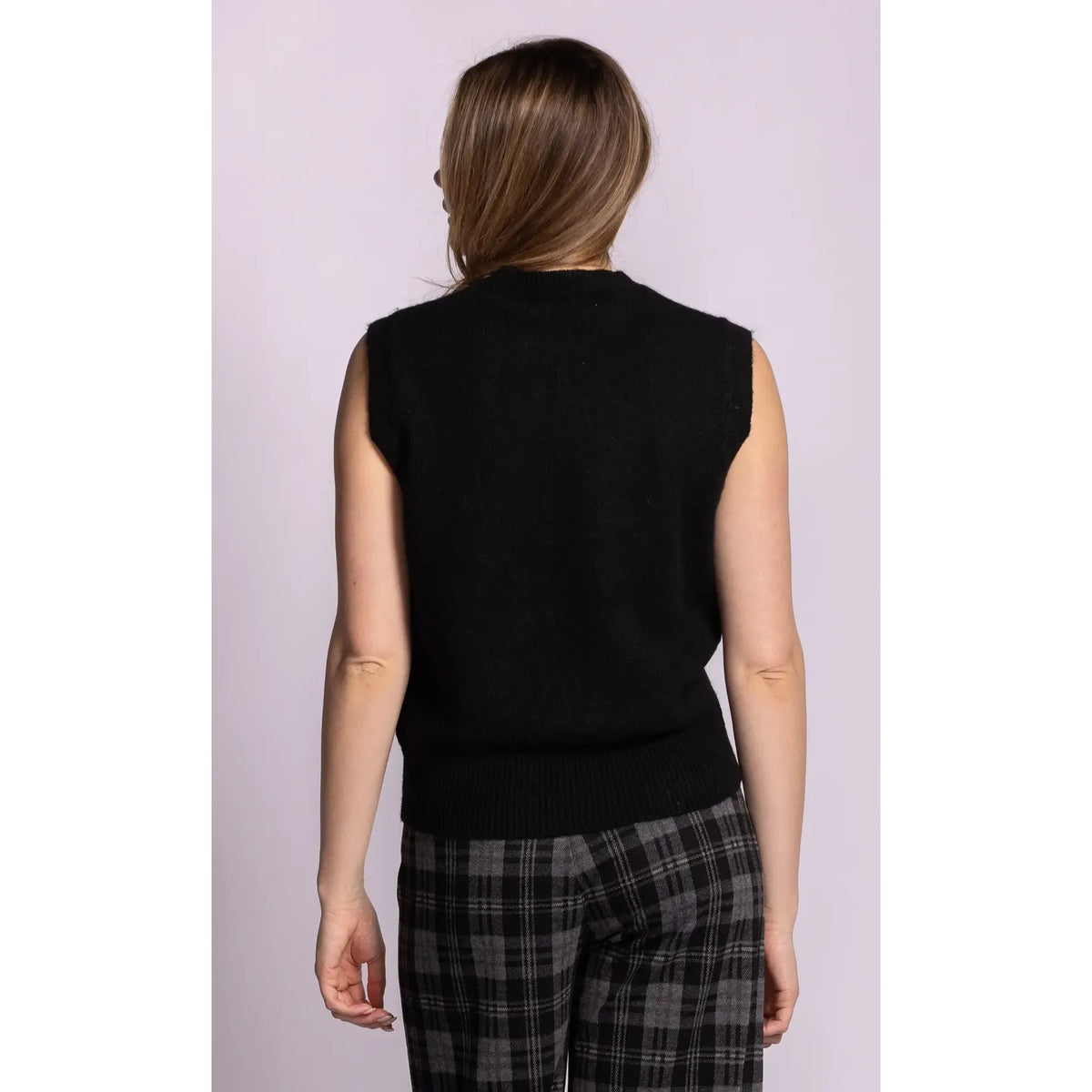 Back view of a black sleeveless ribbed sweater with structured shoulders and hem, styled with plaid pants.
