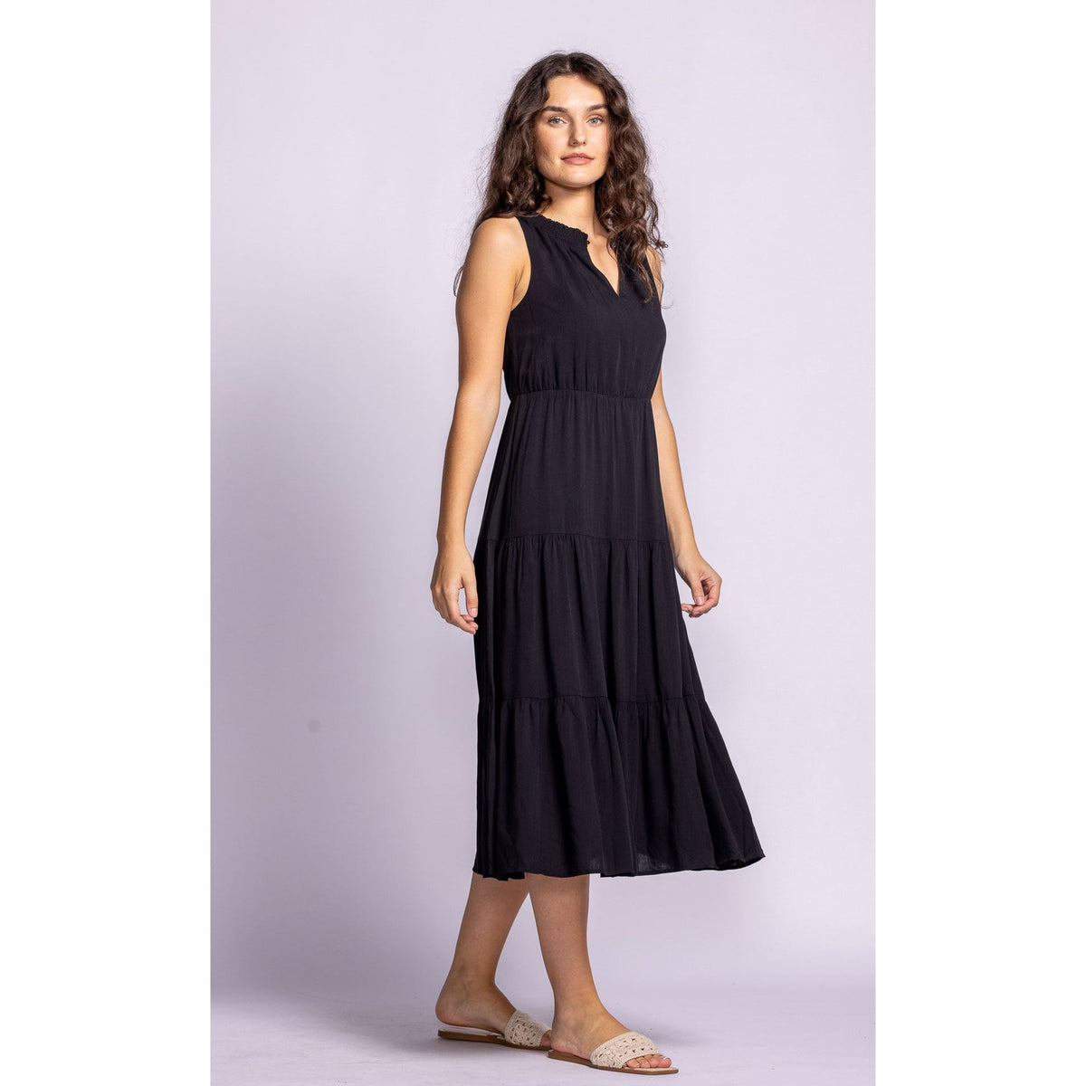 Stylish model showcasing the Pink Martini Jennifer Dress, a chic tiered black midi made from lightweight rayon.