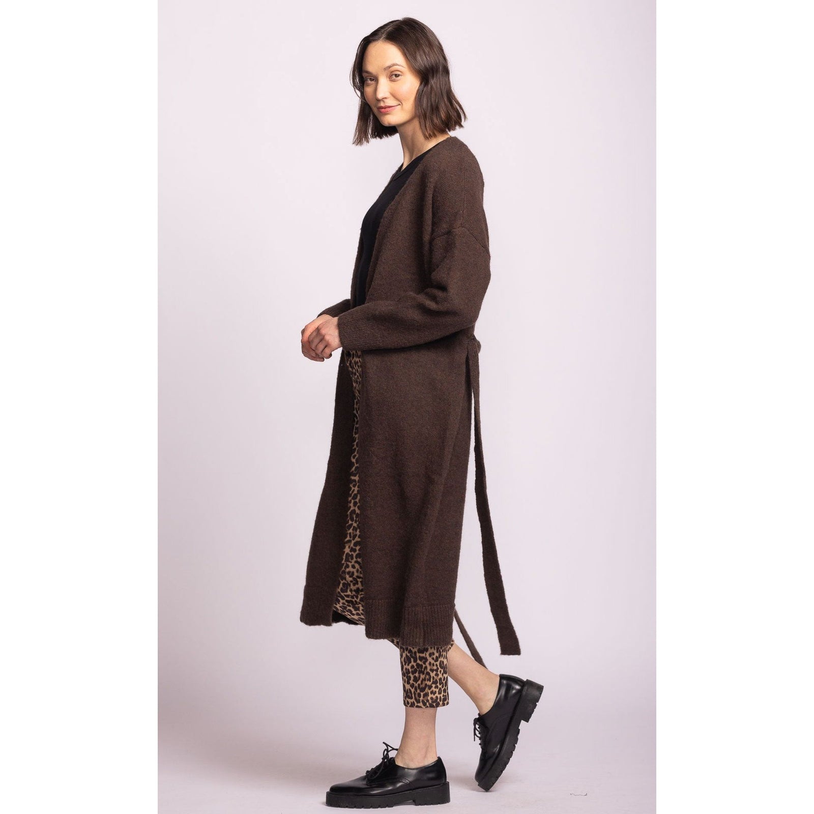 Pink Martini Kiki Sweater: long belted brown cardigan on a model with leopard-print pants for bold autumn layering.