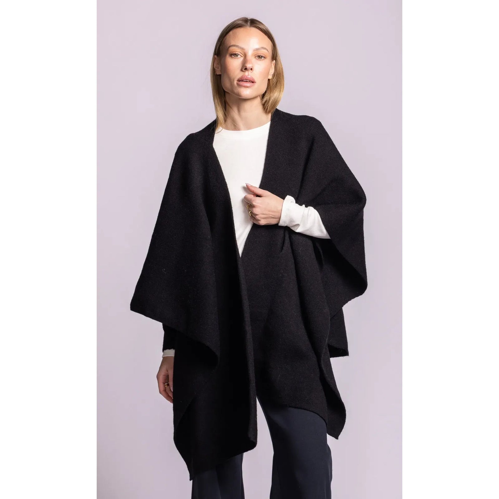 Black Lennon wrap sweater featuring a soft knit poncho silhouette, asymmetric hem, and adaptable waist tie worn open over a white top.