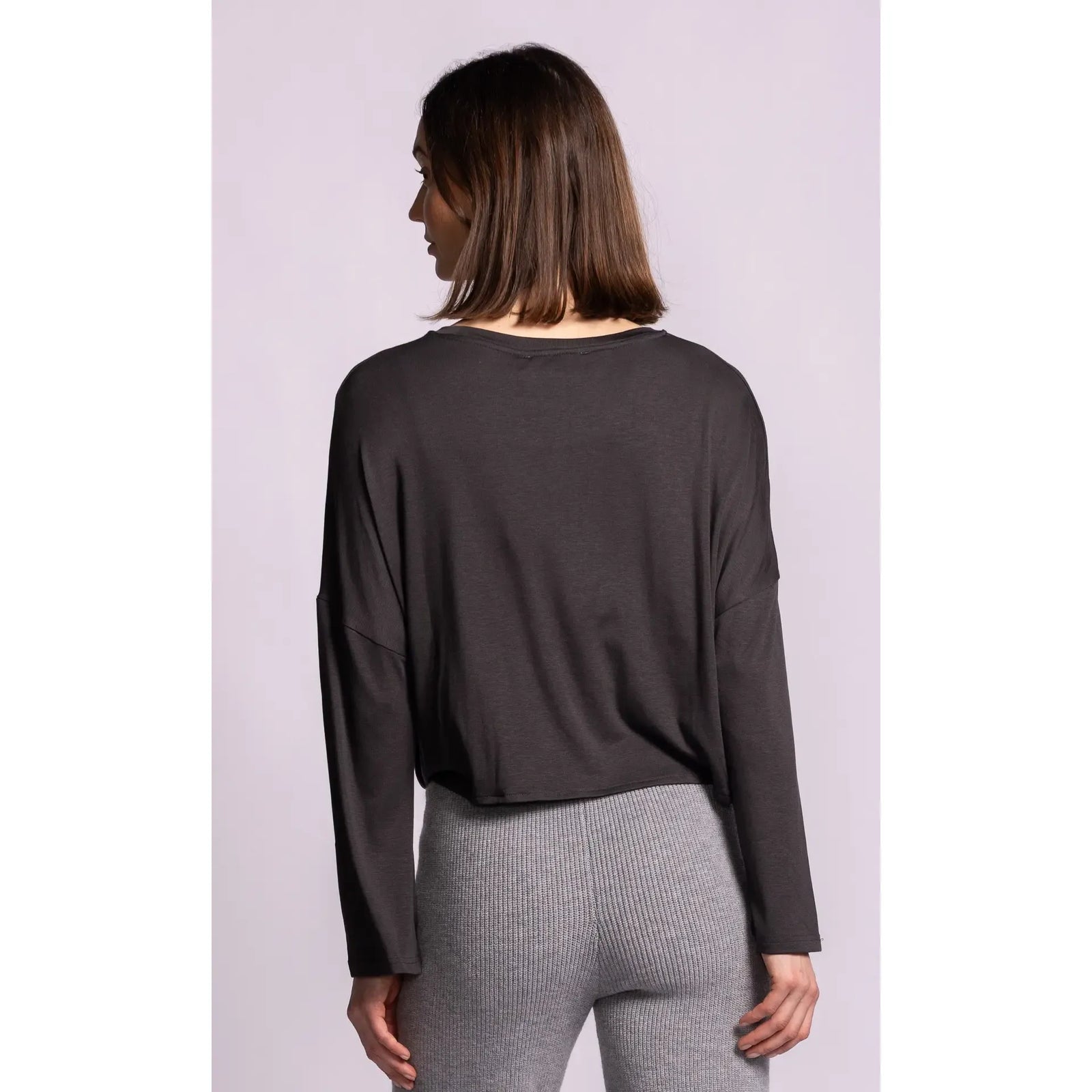 Back view of a dark grey Lenova top featuring relaxed dropped shoulders, soft lightweight drape, and a cropped fit paired with grey knit pants.