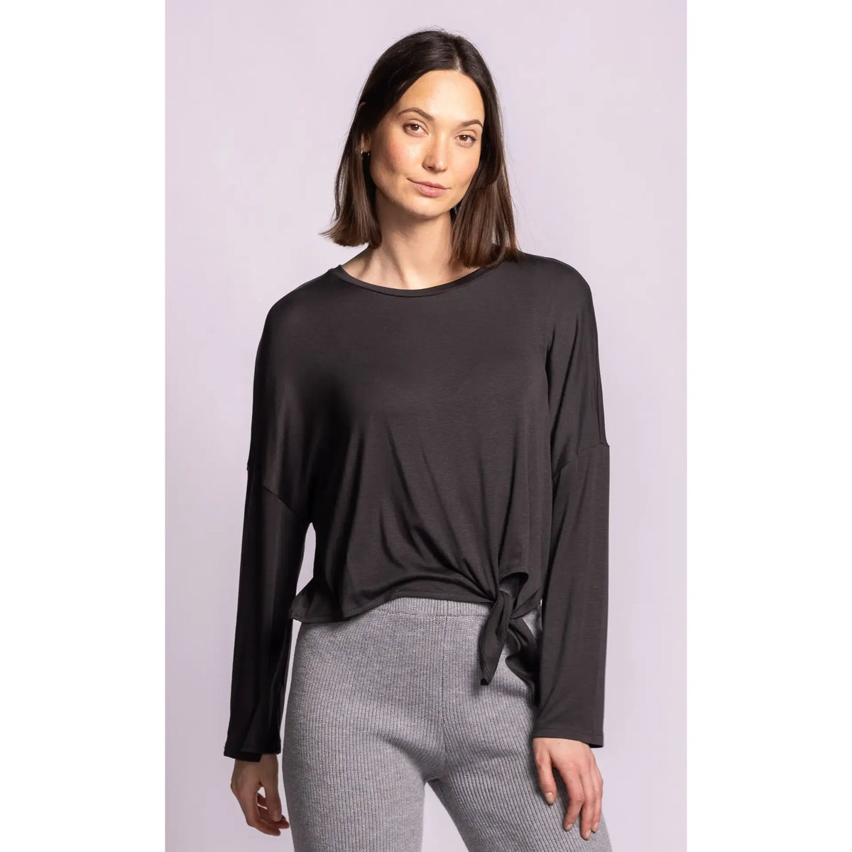 Model wearing a soft black long sleeve top featuring relaxed dropped shoulders and a charming side self-tie knot detail for effortless style.