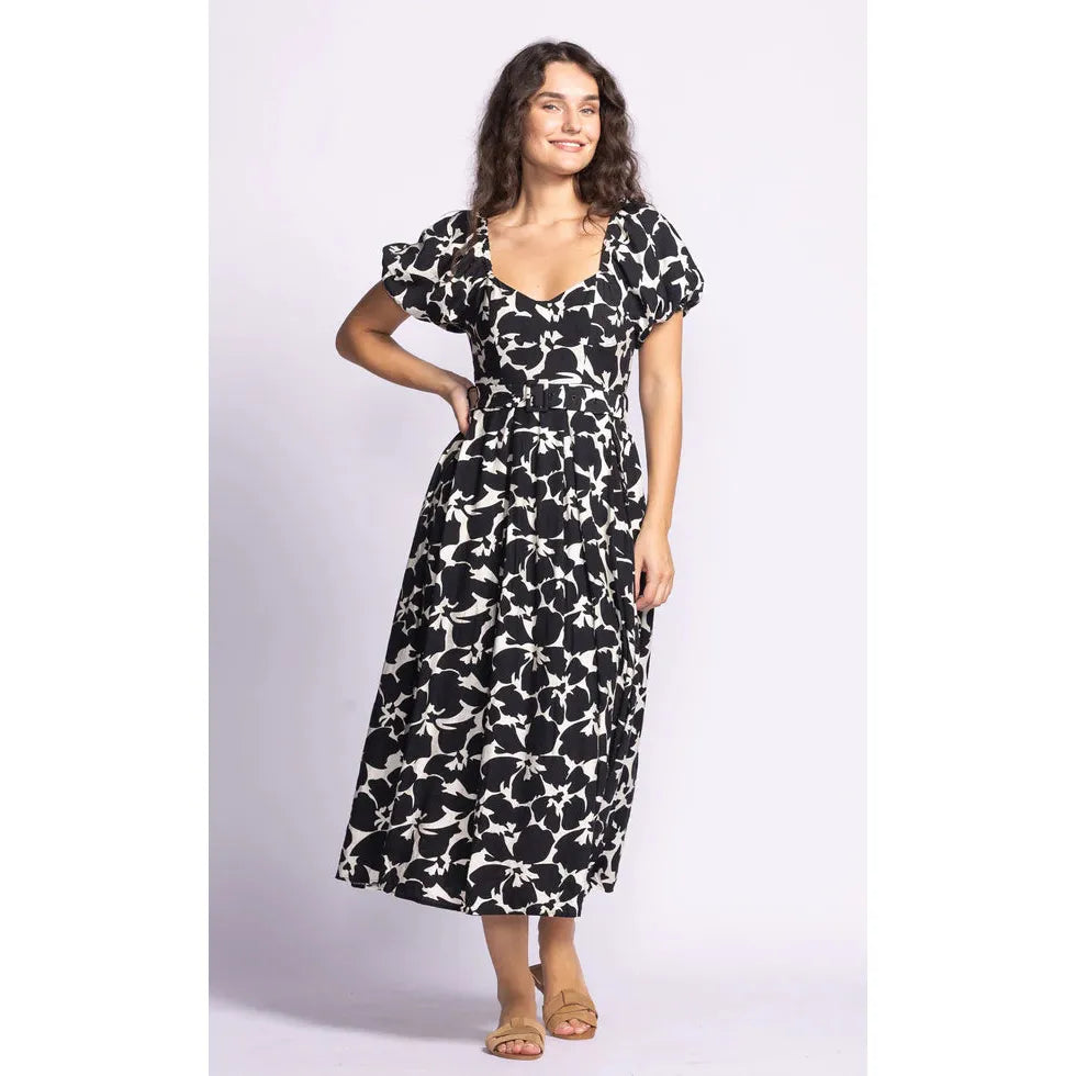 Stylish model wearing the Pink Martini Rachel Dress, featuring puffed sleeves and a floral design, perfect for any occasion.