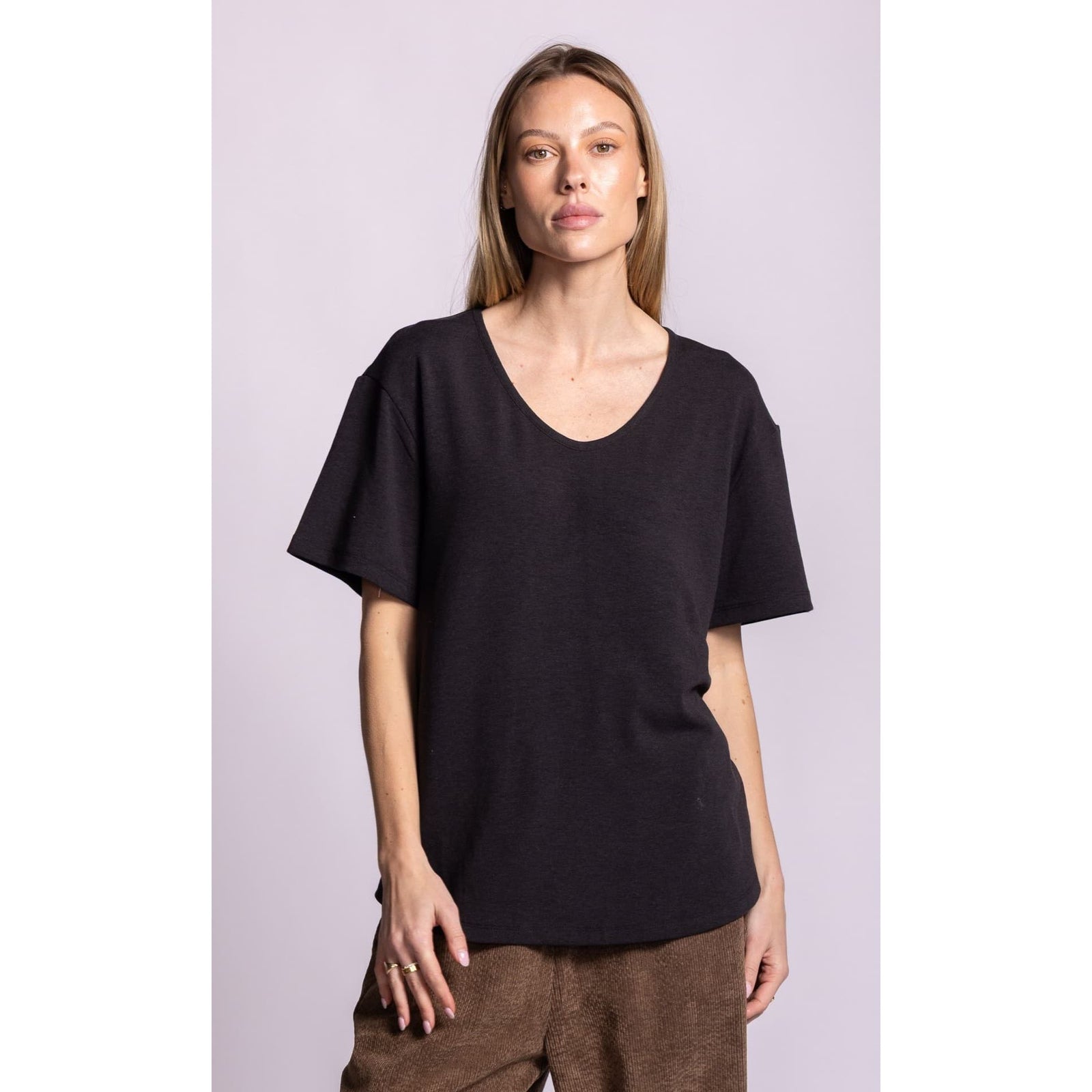 Model wearing a dark charcoal relaxed fit scoop neck top with dropped shoulders and short sleeves over brown corduroy pants.