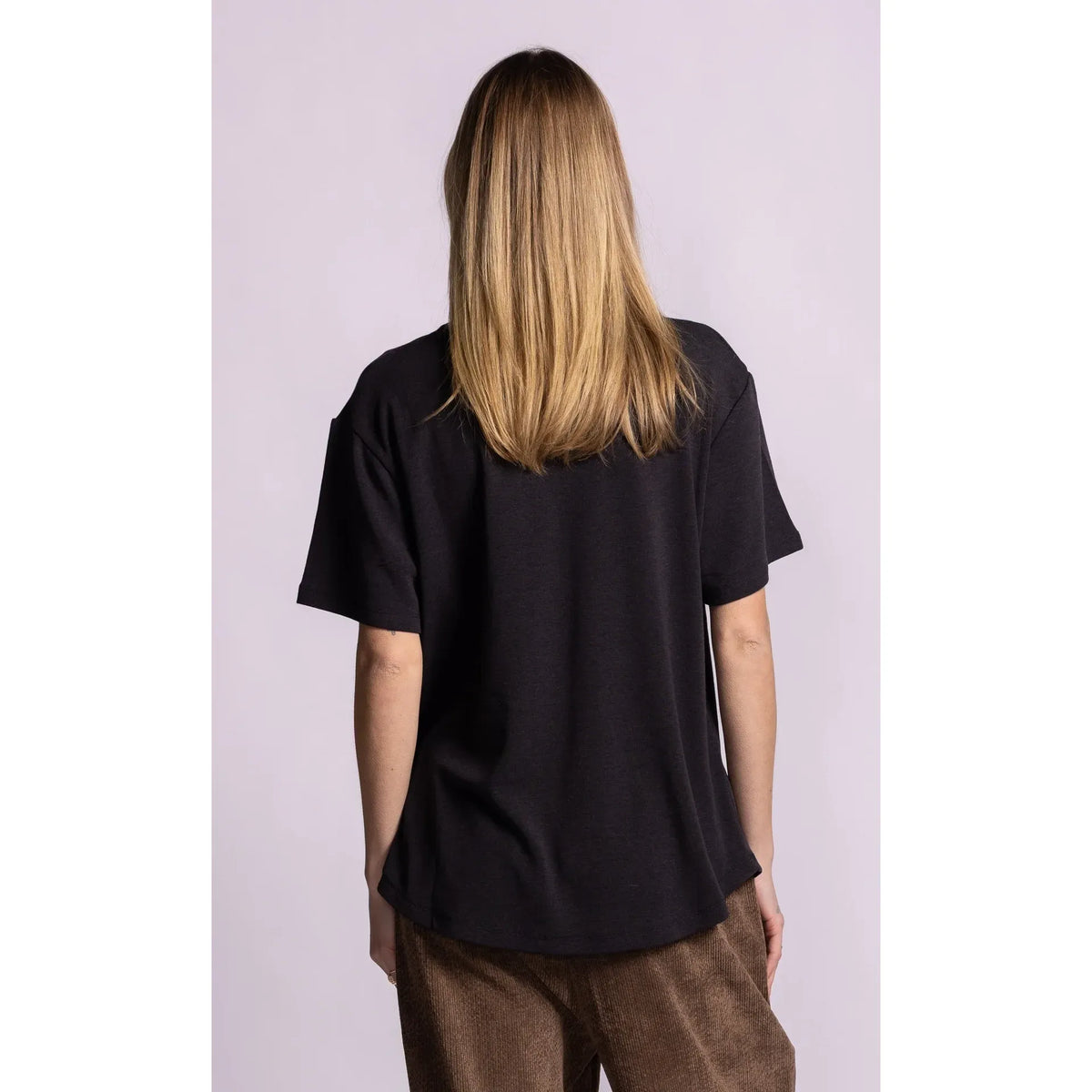 Back view of a relaxed fit black short sleeve top with dropped shoulders and a cozy brushed lining.