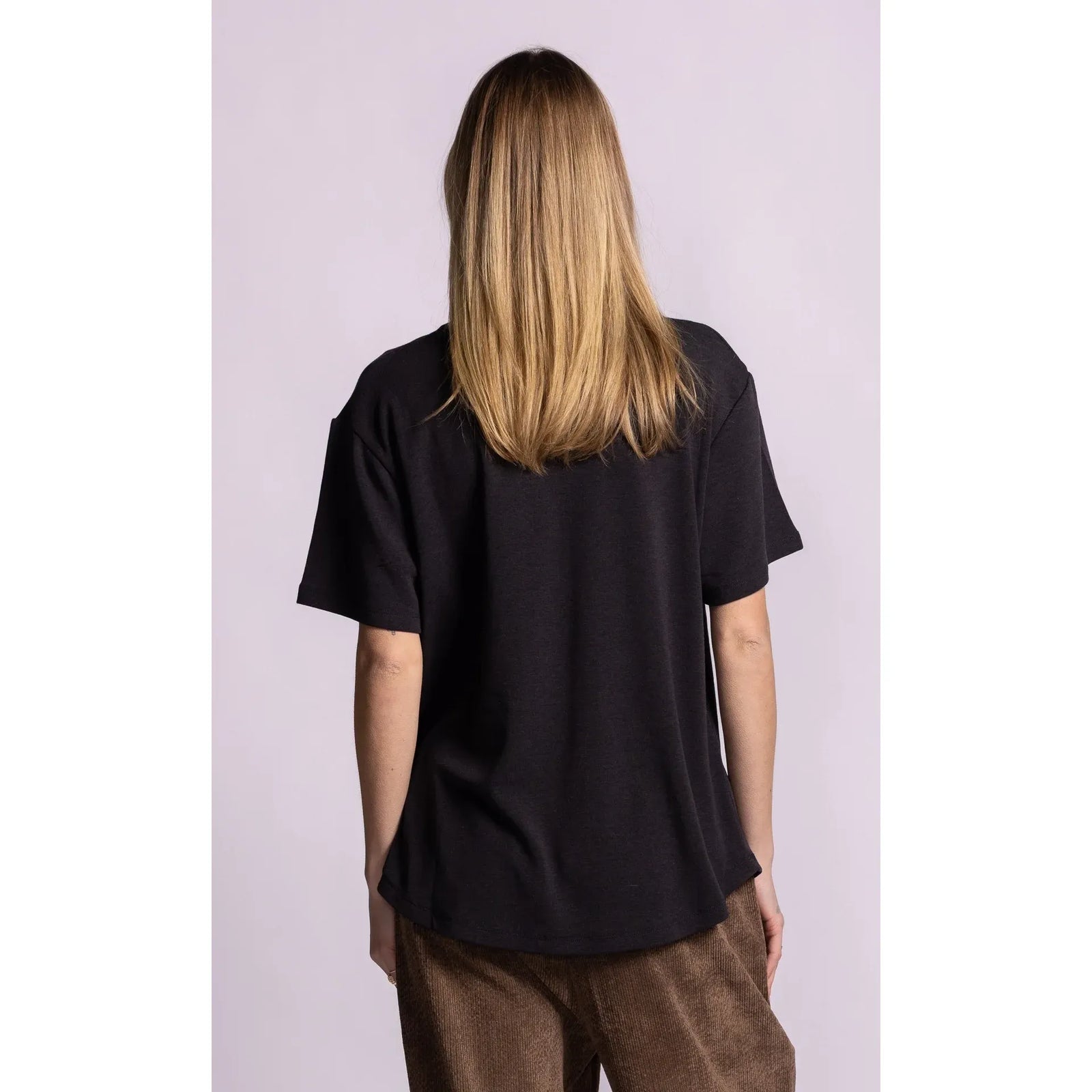 Back view of a relaxed fit black short sleeve top with dropped shoulders and a cozy brushed lining.