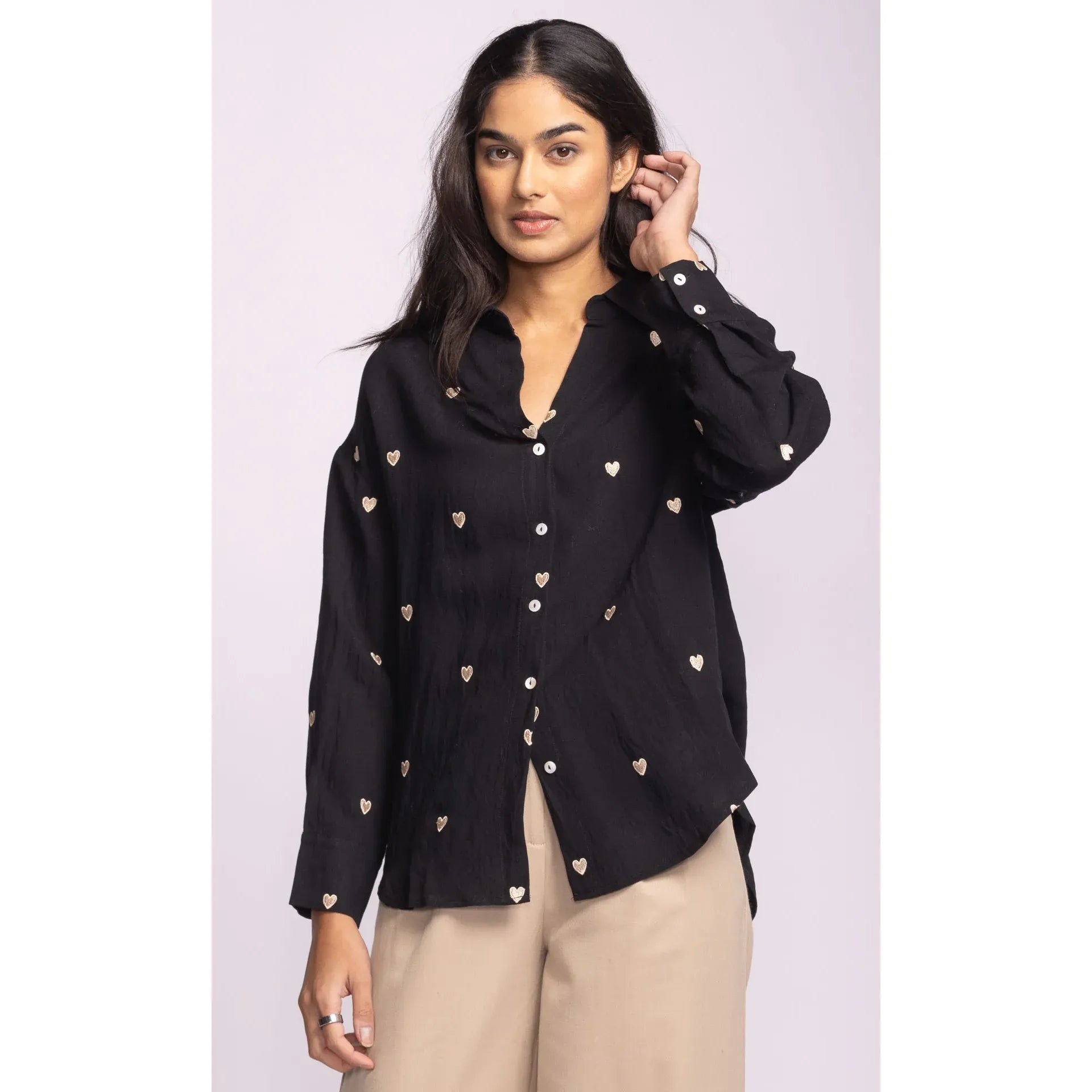 Pink Martini Spezia Topp black top with delicate embroidered hearts, classic collar, V-neck, and buttoned cuffs.