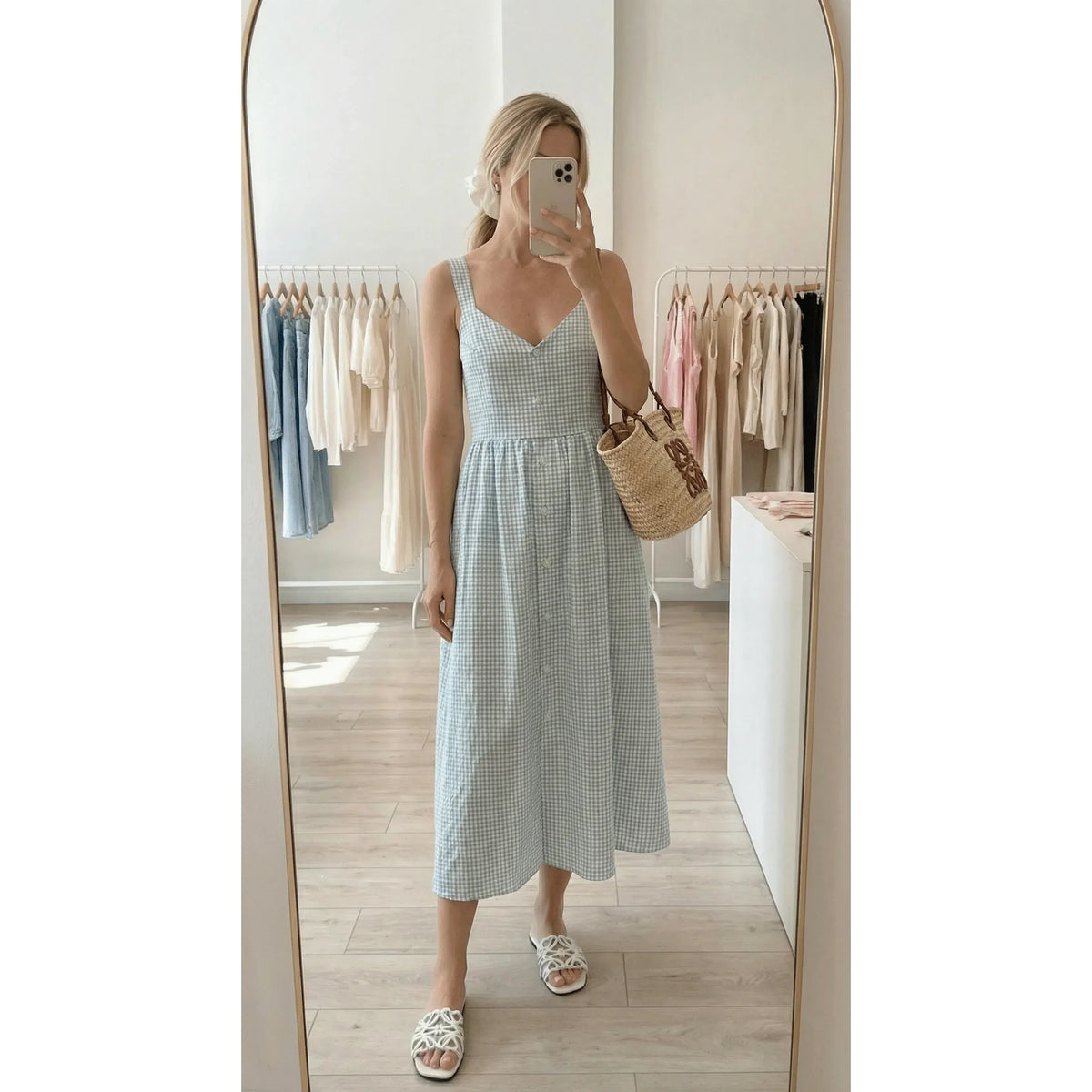Woman wearing blue gingham Priv Estelle button-down cotton dress, sleeveless midi length, with woven straw tote.