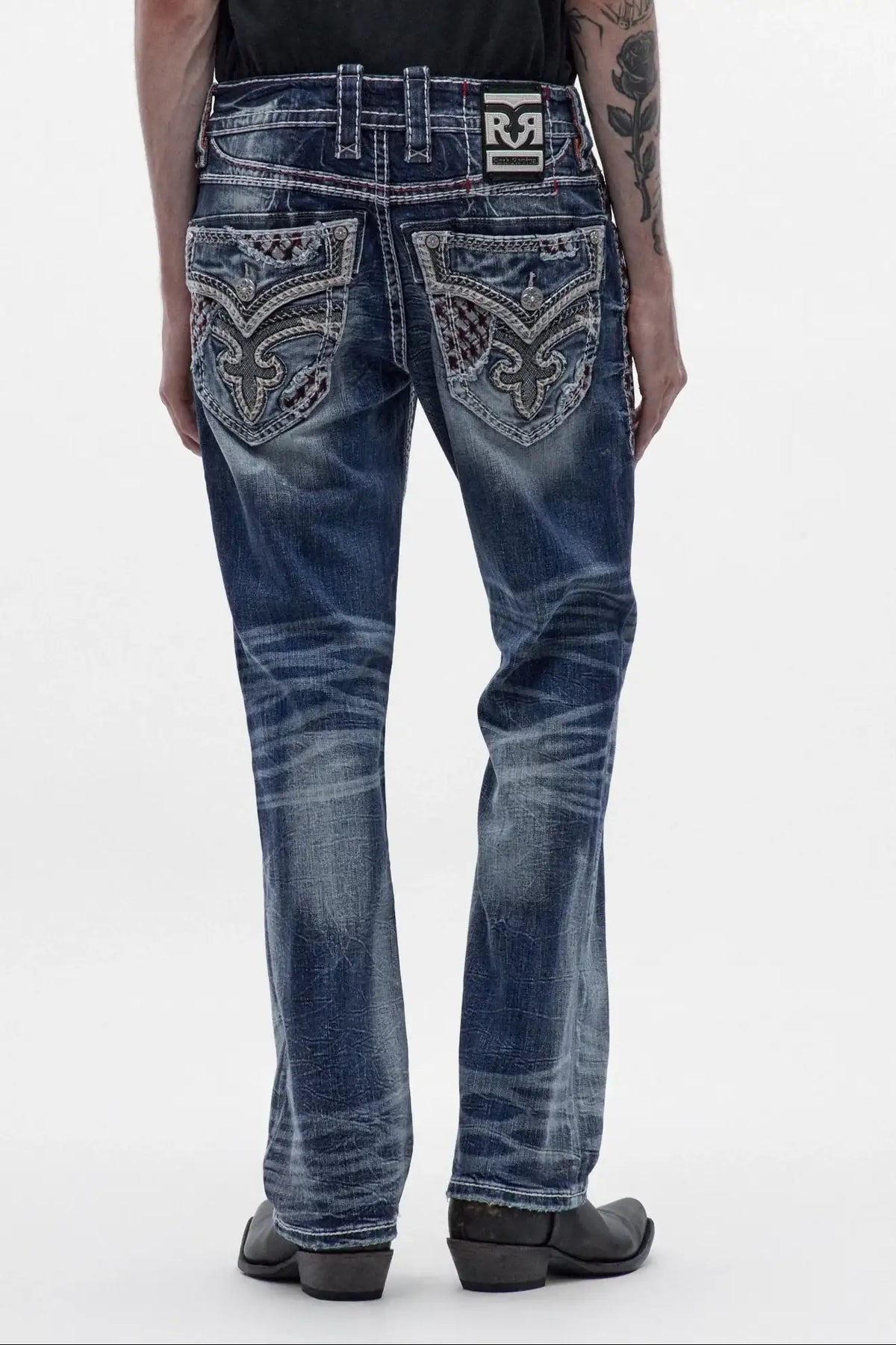 Men's medium blue bootcut jeans featuring ornate back pocket embroidery, whiskering, and a classic boot leg fit.