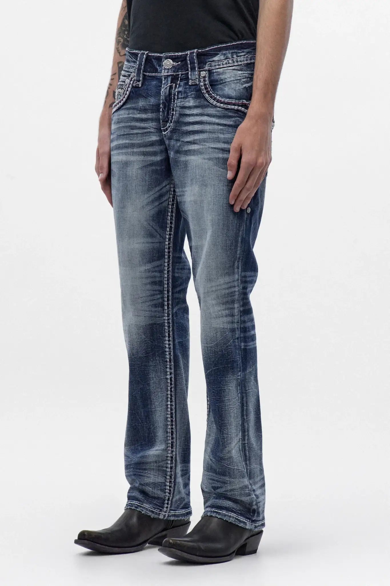 Men's medium blue wash bootcut jeans with signature side stitching and embroidered back pockets, styled with black cowboy boots.