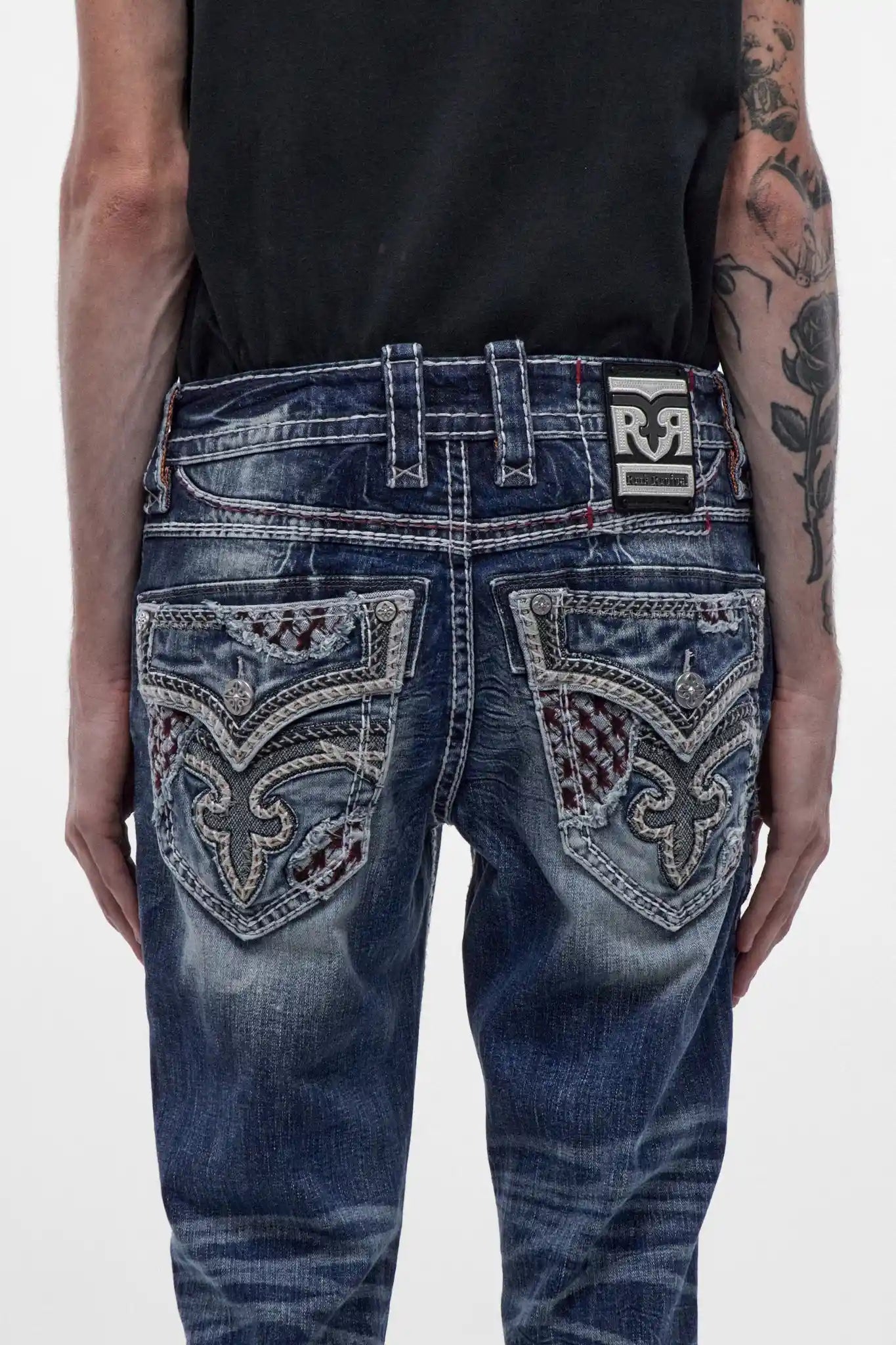 Back view of medium blue bootcut jeans featuring elaborate back pocket embroidery and a metal waist patch logo.
