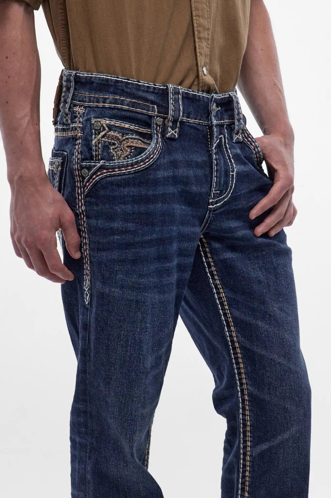Dark blue men's bootcut jeans featuring signature fleur-de-lis back pocket embroidery and decorative contrast stitching along the seams.