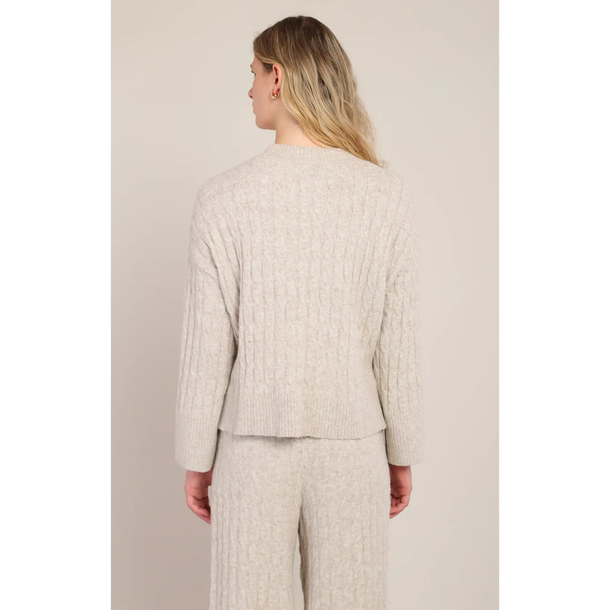 Back view of beige cable knit sweater with crew neck and matching pants, showcasing cozy wool blend texture for cold weather.