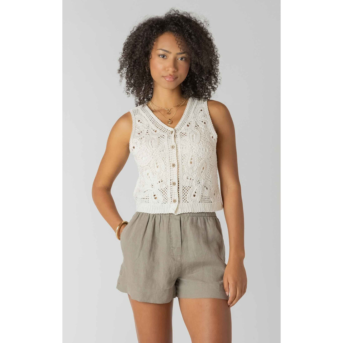Room 34 crochet buttoned vest in ivory worn by model with khaki shorts.