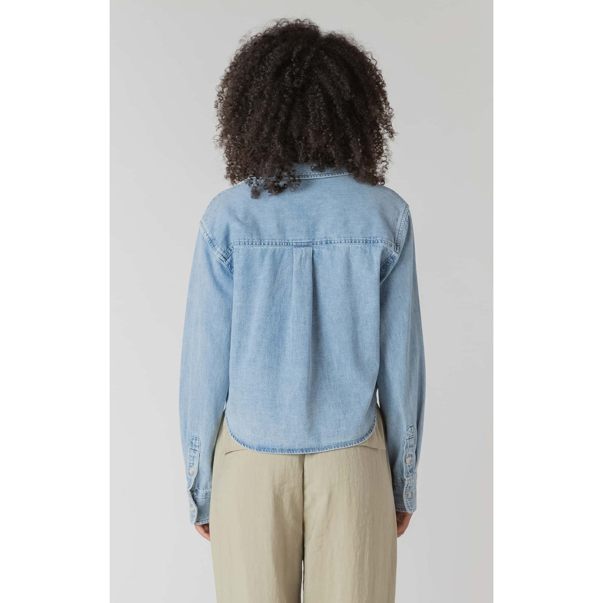 Back view of Room 34 Lightweight Denim Shirt in light denim with long sleeves and cropped hem.