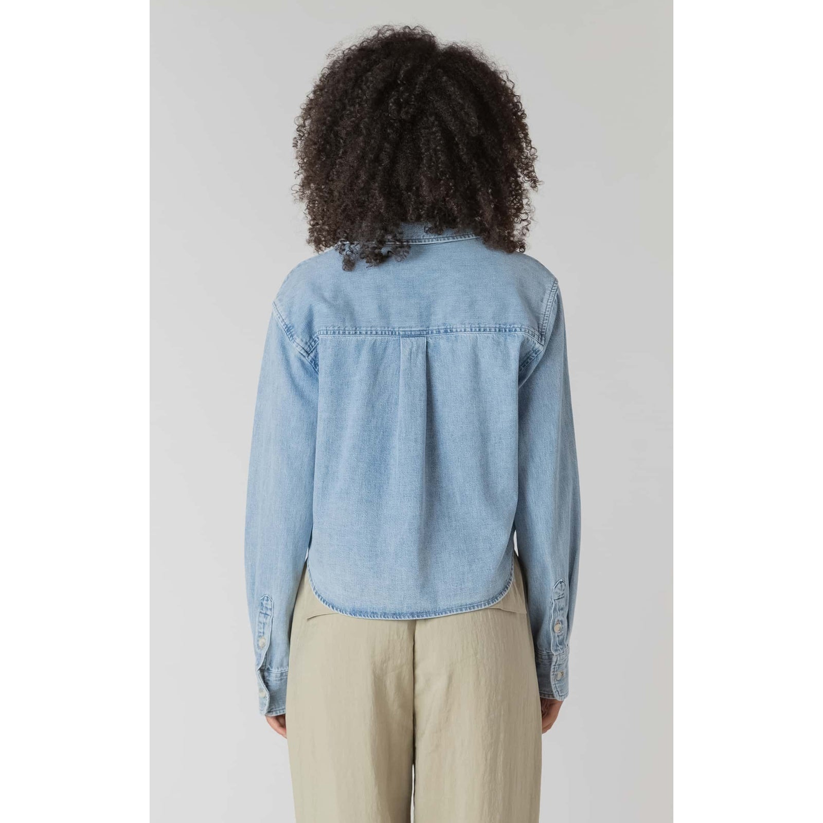 Back view of Room 34 Lightweight Denim Shirt in light denim with long sleeves and cropped hem.