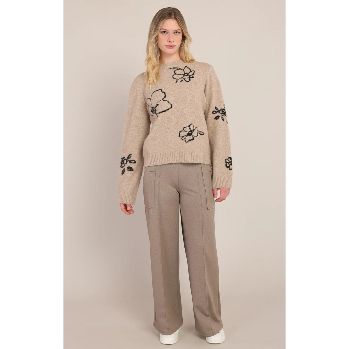 Taupe crewneck sweater featuring black contrast floral accents on the body and sleeves, styled with matching wide-leg trousers.