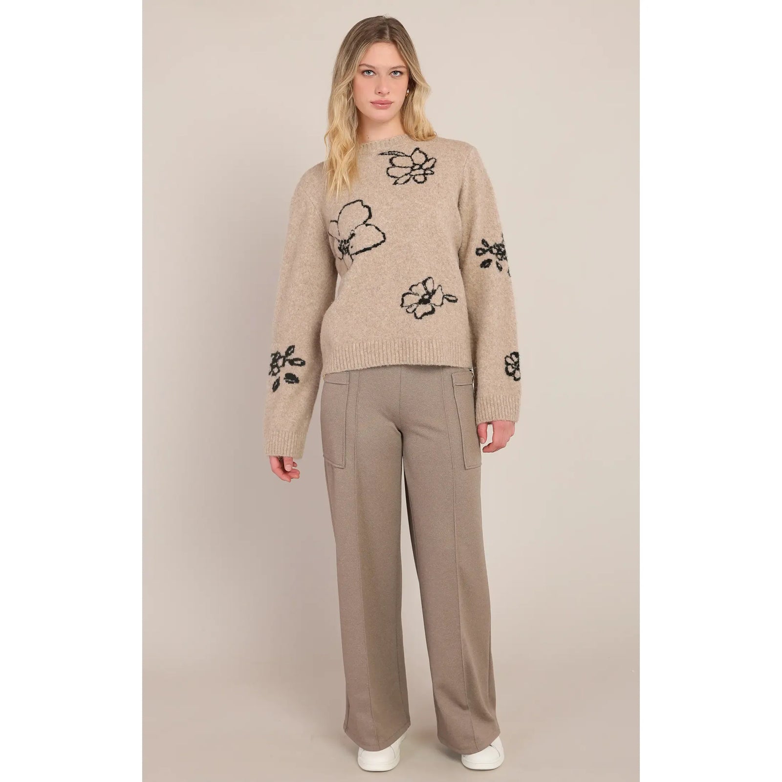 Taupe crewneck sweater featuring black contrast floral accents on the body and sleeves, styled with matching wide-leg trousers.