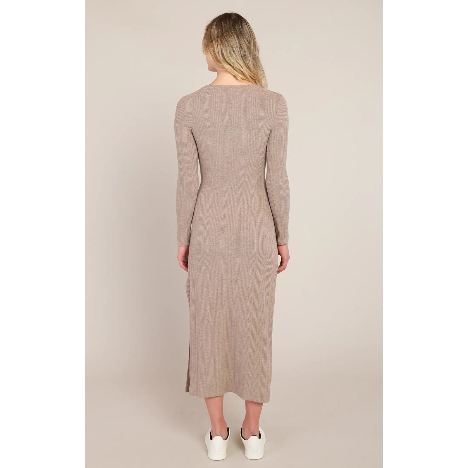 Back view of beige ribbed long dress with long sleeves and side slit. Knot waist detail defines the silhouette for elegant fall styling.