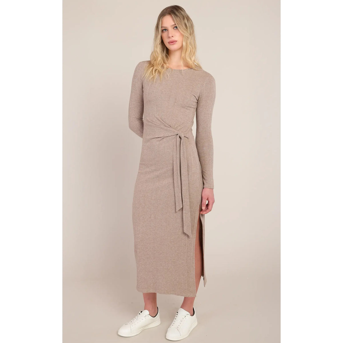 Beige ribbed long dress featuring a signature knotted waist detail and side slit, styled with white sneakers for versatile fall elegance.