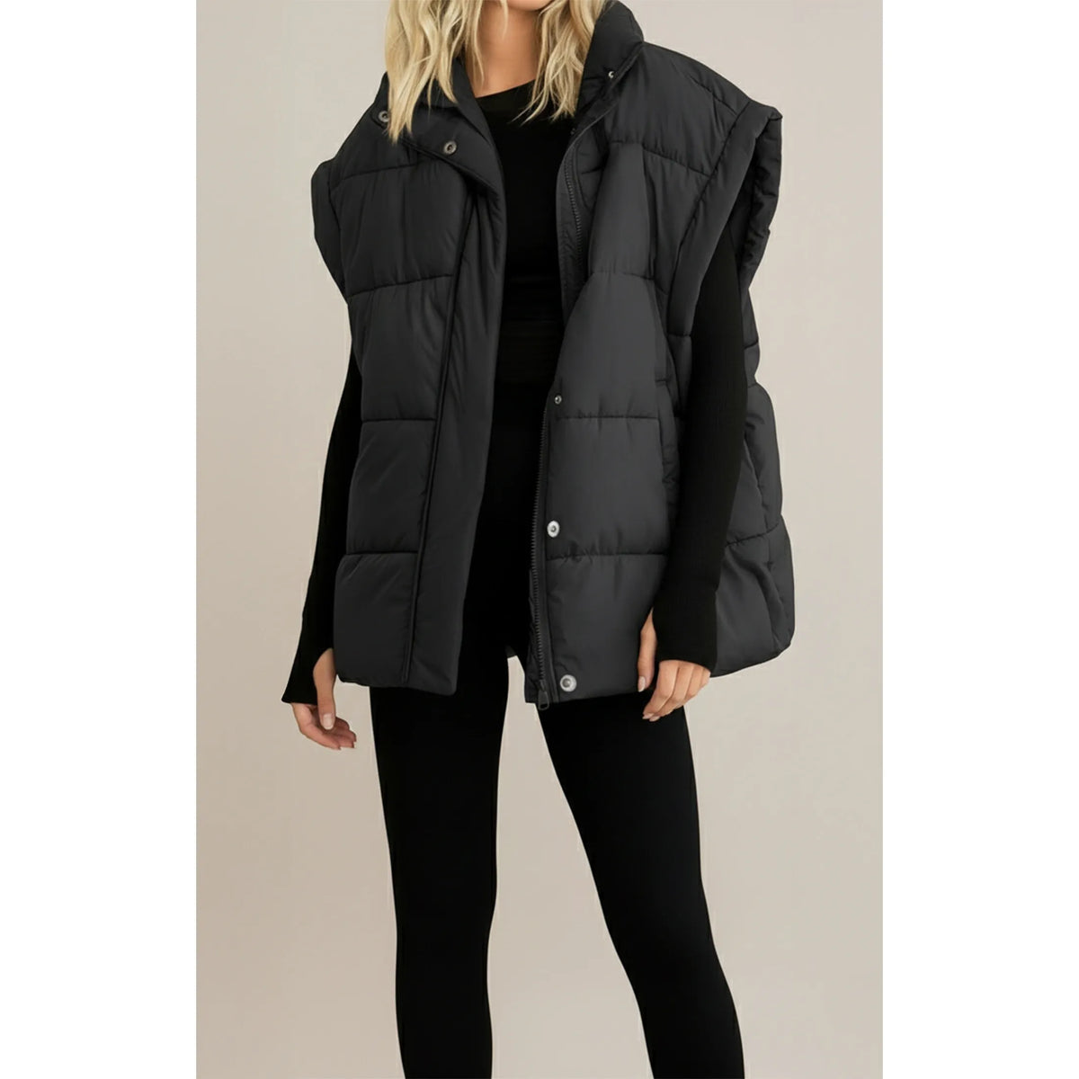 Black quilted boxy vest with high collar and zip front, styled over a black top and leggings for cool weather.