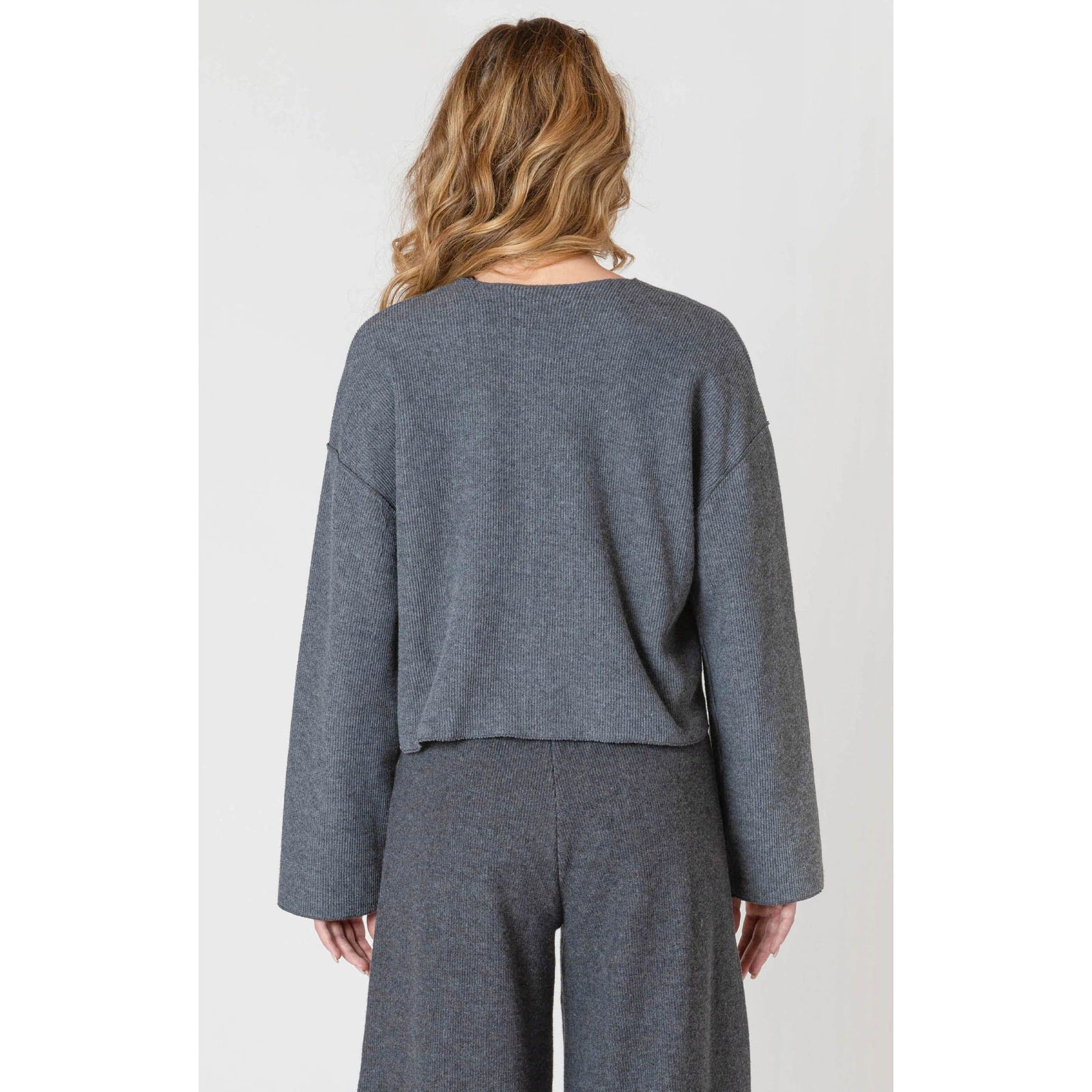 Back view of a model wearing the Room 34 Ribbed Cardigan in gray with long sleeves and a loose fit.
