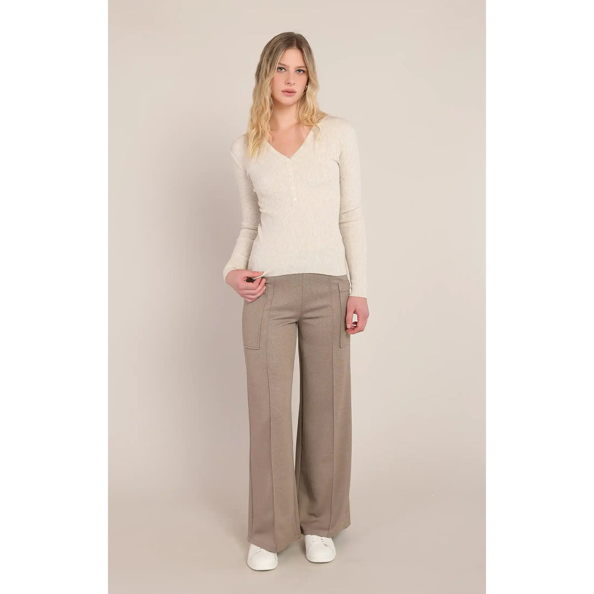 Cream ribbed V-neck sweater with long sleeves, styled with wide-leg beige trousers and white sneakers for a cozy, versatile look.